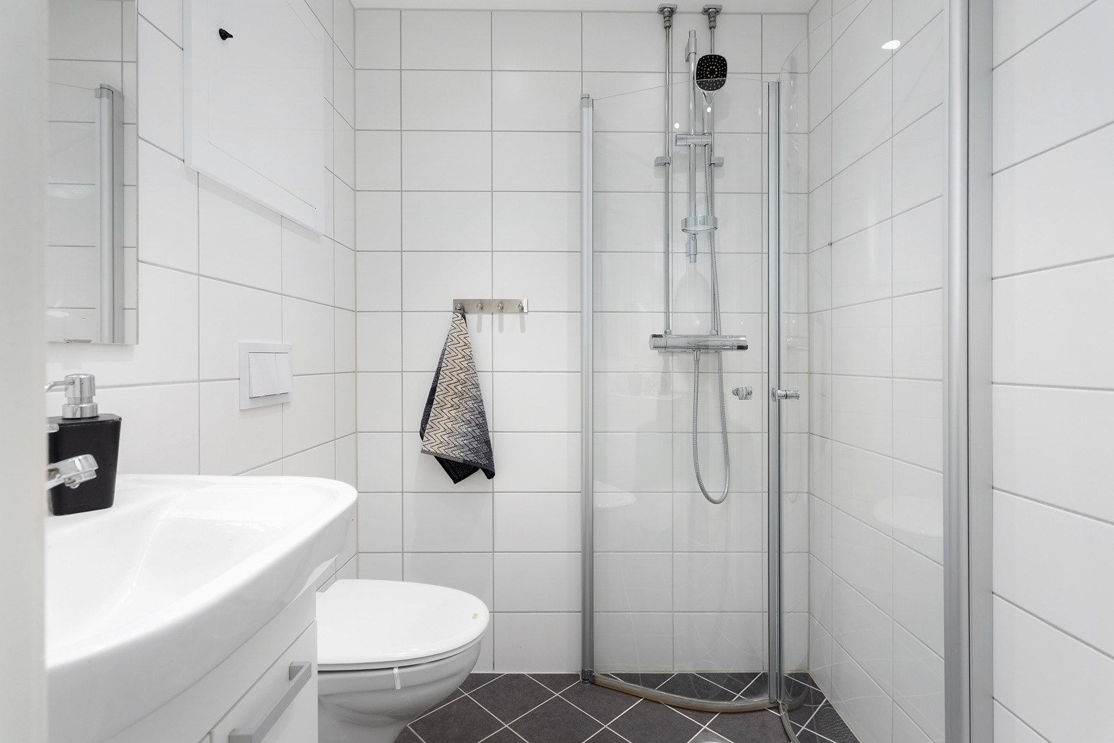 Meget pent flislagt baderom fra 2019 utført i regi av borettslaget! Innredningen består av servant, vegghengt toalett samt. dusj på gulv med innfellbare dusjdører. Galleribilde
