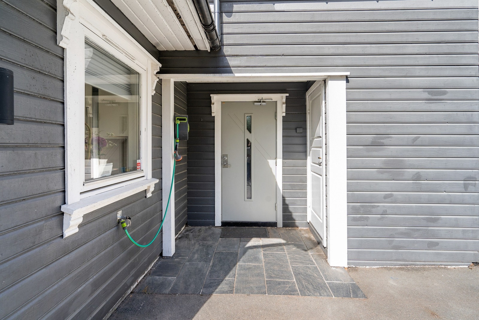 Flislagt og overbygd inngangsparti med bod til høyre Galleribilde