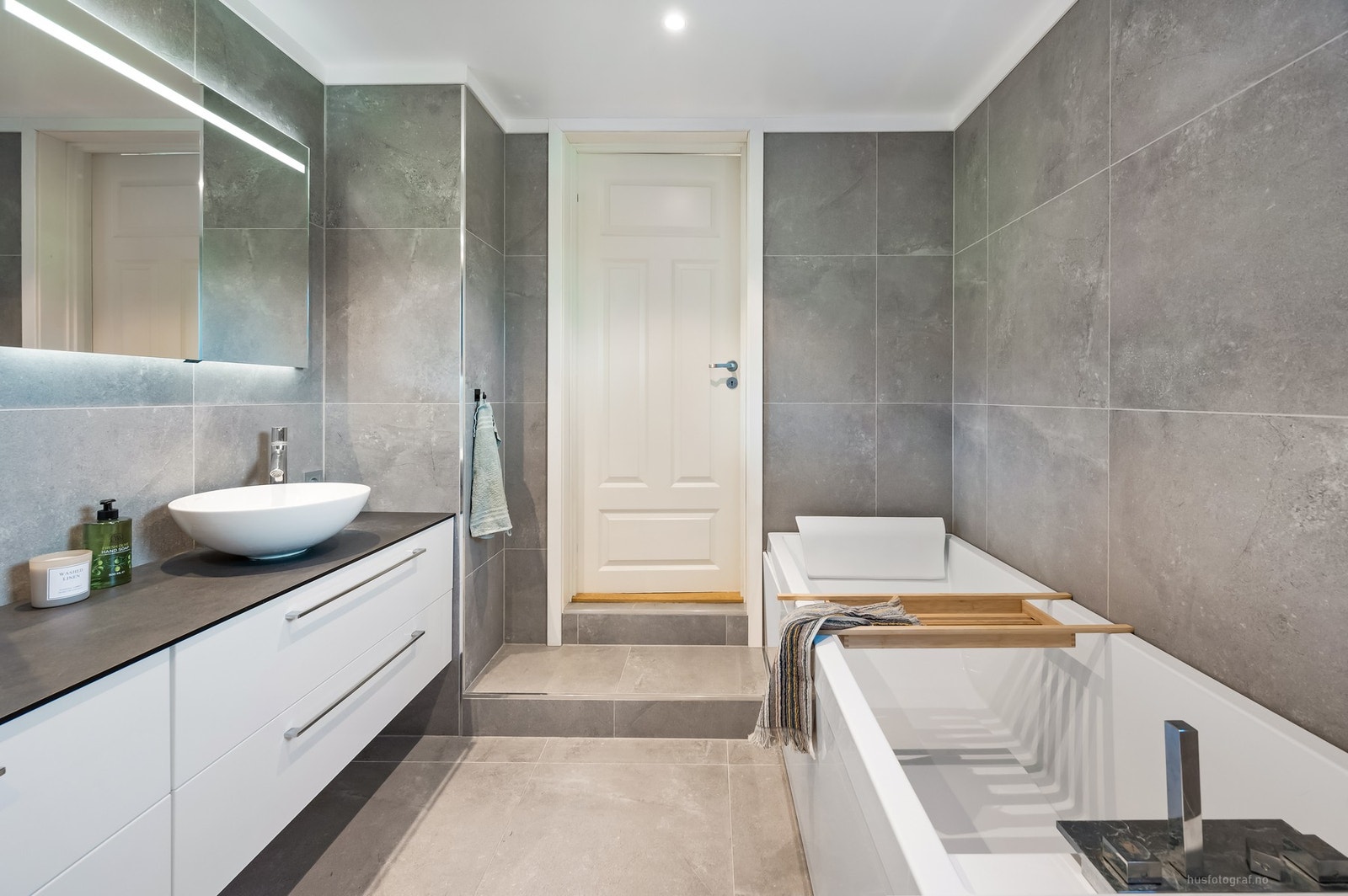 Badet har flislagte overflater, downlights i himling og er innredet med toalett, badekar og servant. Galleribilde