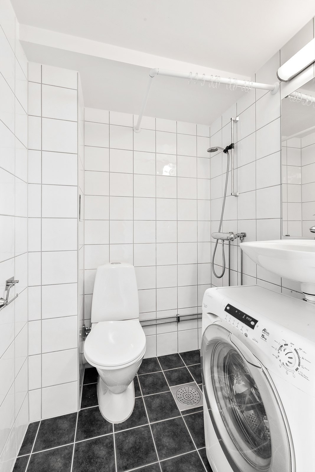 Badet er utstyrt med dusjhjørne med forheng, gulvstående WC og enkel servant. Det er også opplegg for vaskemaskin. Galleribilde