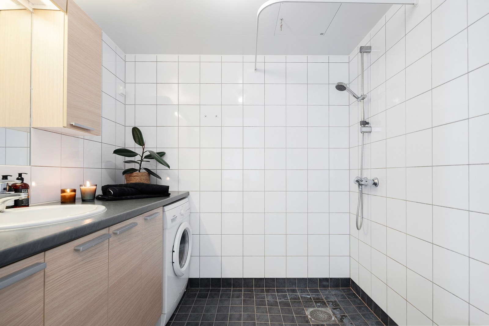 Flislagt bad med mye lagringsplass i innredningen, samt god plass til vaskemaskin Galleribilde