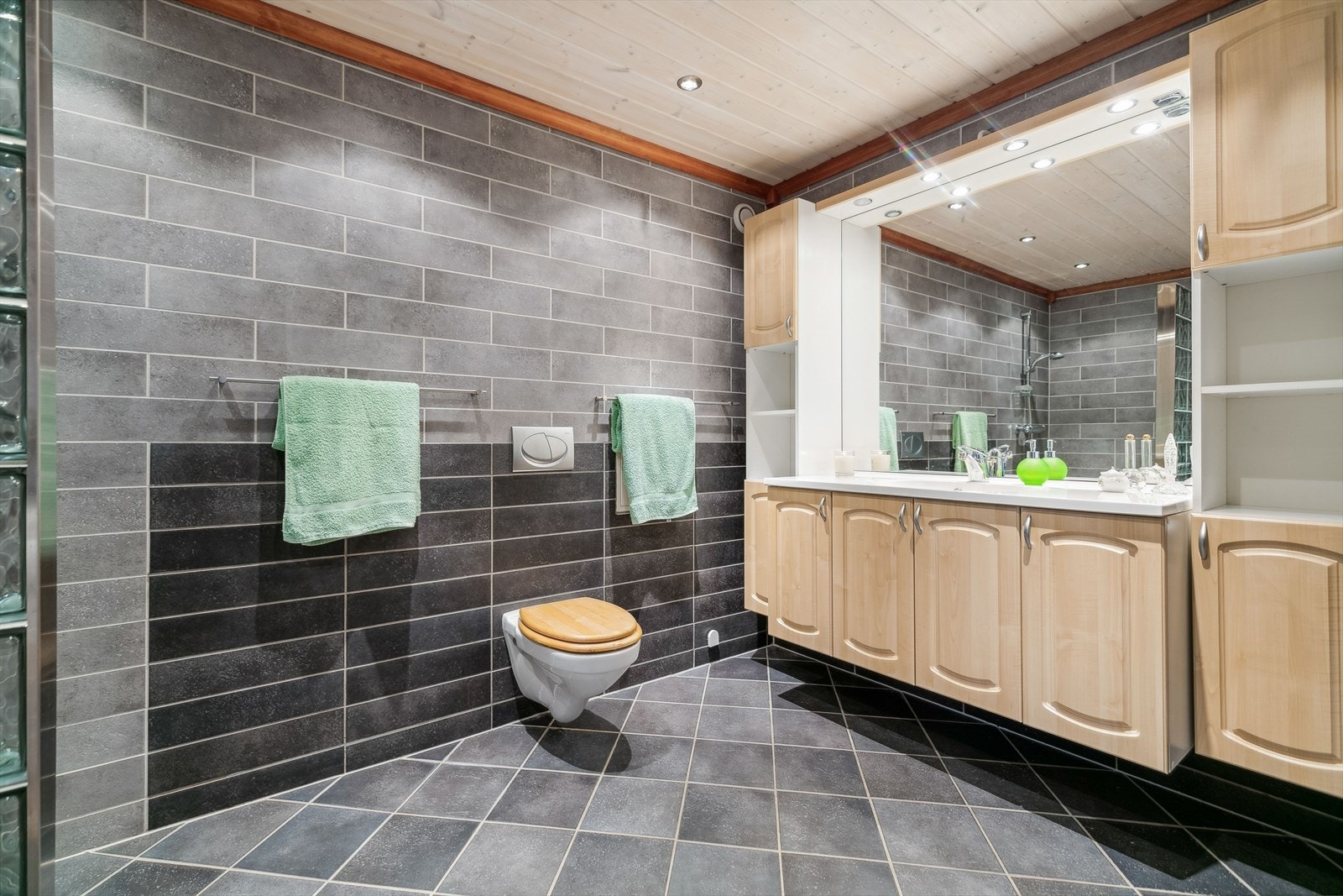 Badet i boligen har flislagte vegger, dusjhjørne med en fastmontert vegg av glassbyggerstein og 2- greps blandebatteri. Galleribilde