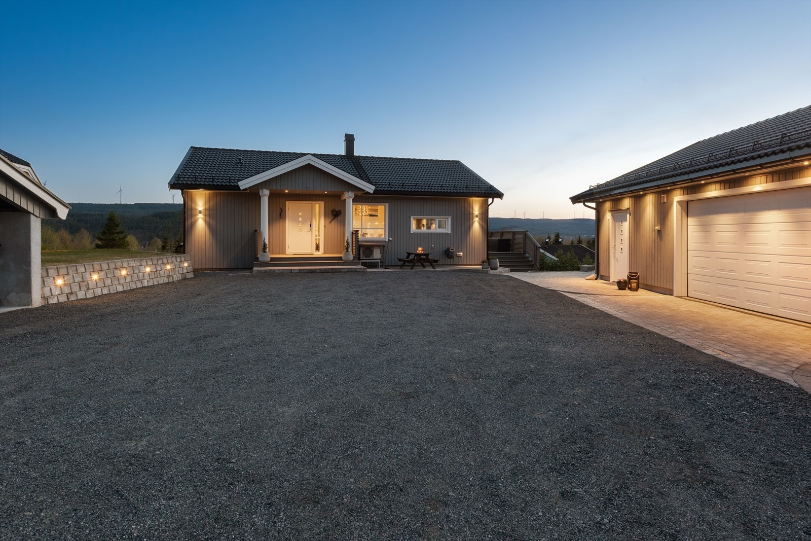 Det er gjennomtenkte belysningsløsninger med både lyssatt støttemur, downlights på garasje og stilige utelamper. Galleribilde