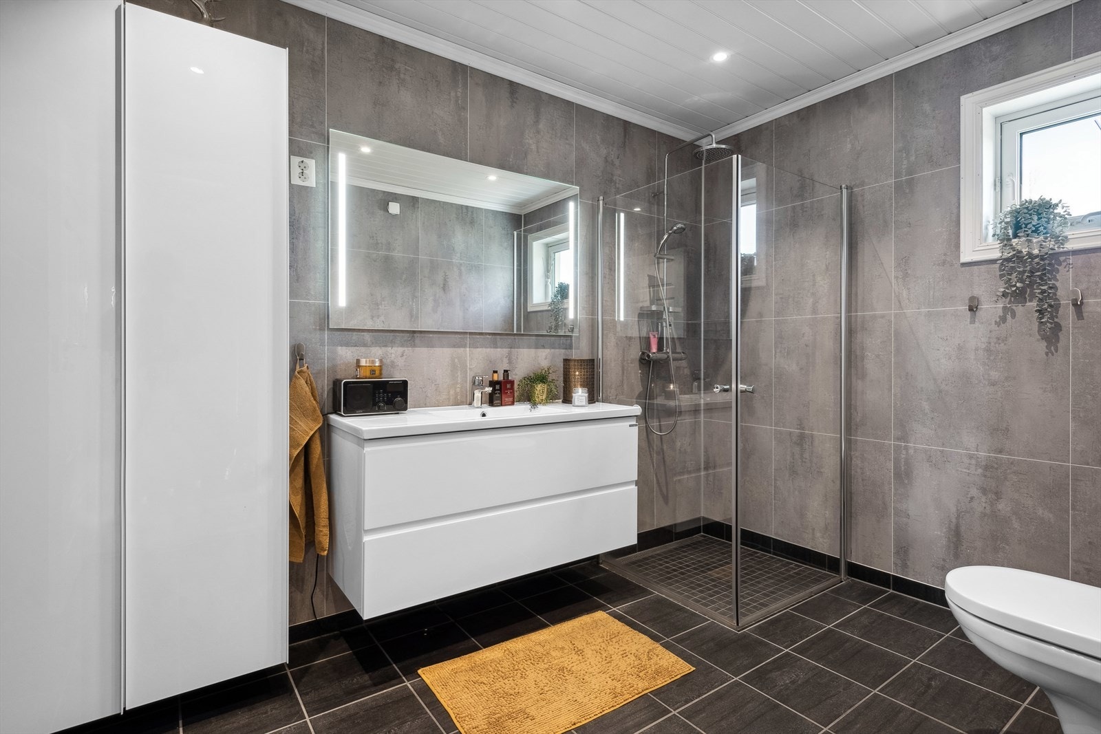 Solid og pent bad med flislagt gulv og baderomsplater på veggene. Galleribilde