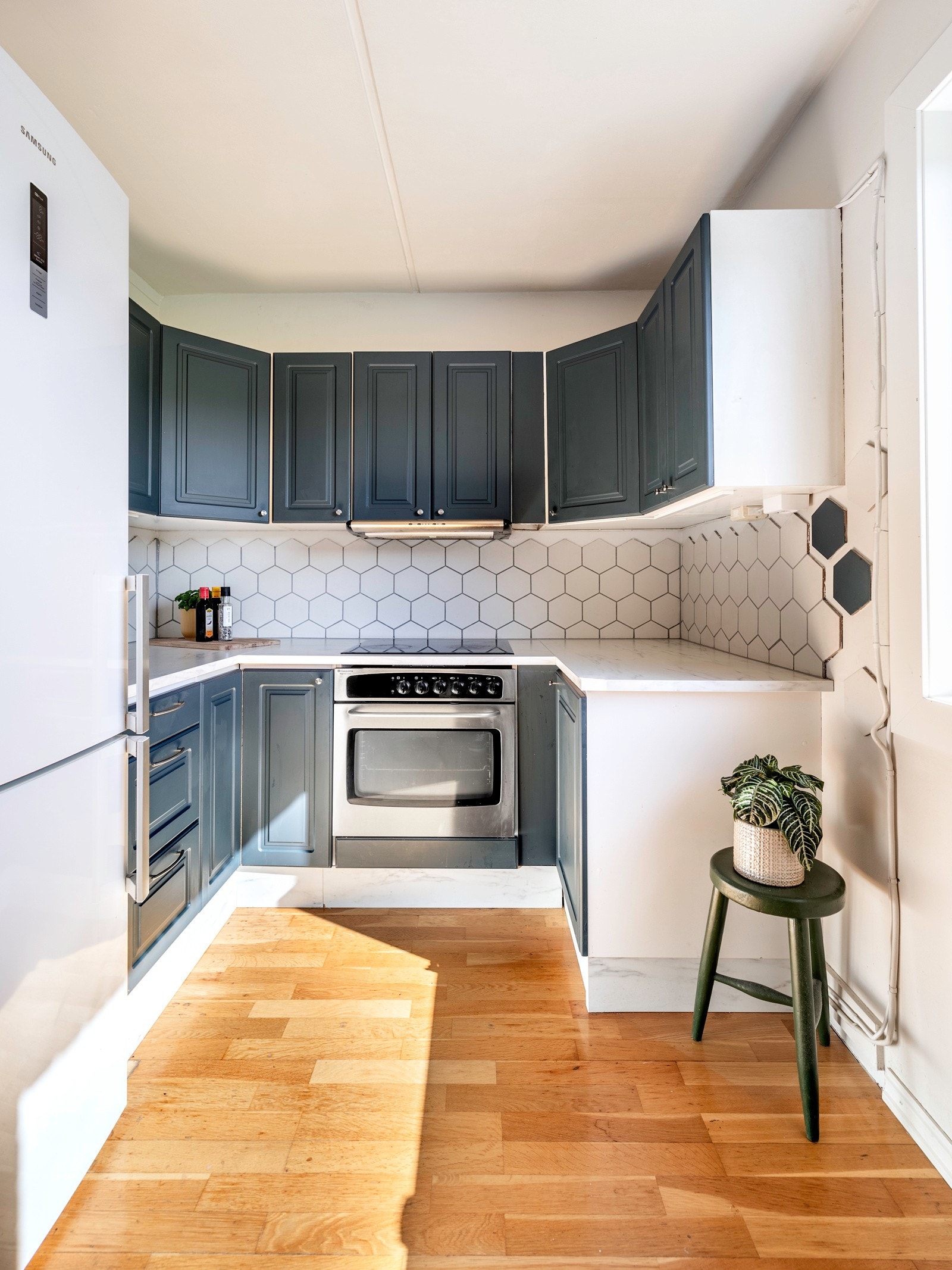 Benkeplater og sokler har marmormønstret laminat og på veggene bak er det heksagonmønstrede fliser i hvitt og blått. Galleribilde