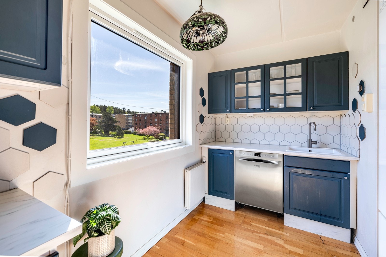 På kjøkkenet er det parkettgulv, hvitmalte vegger og et vindu som vender ut mot de fine fellesområdene. Galleribilde