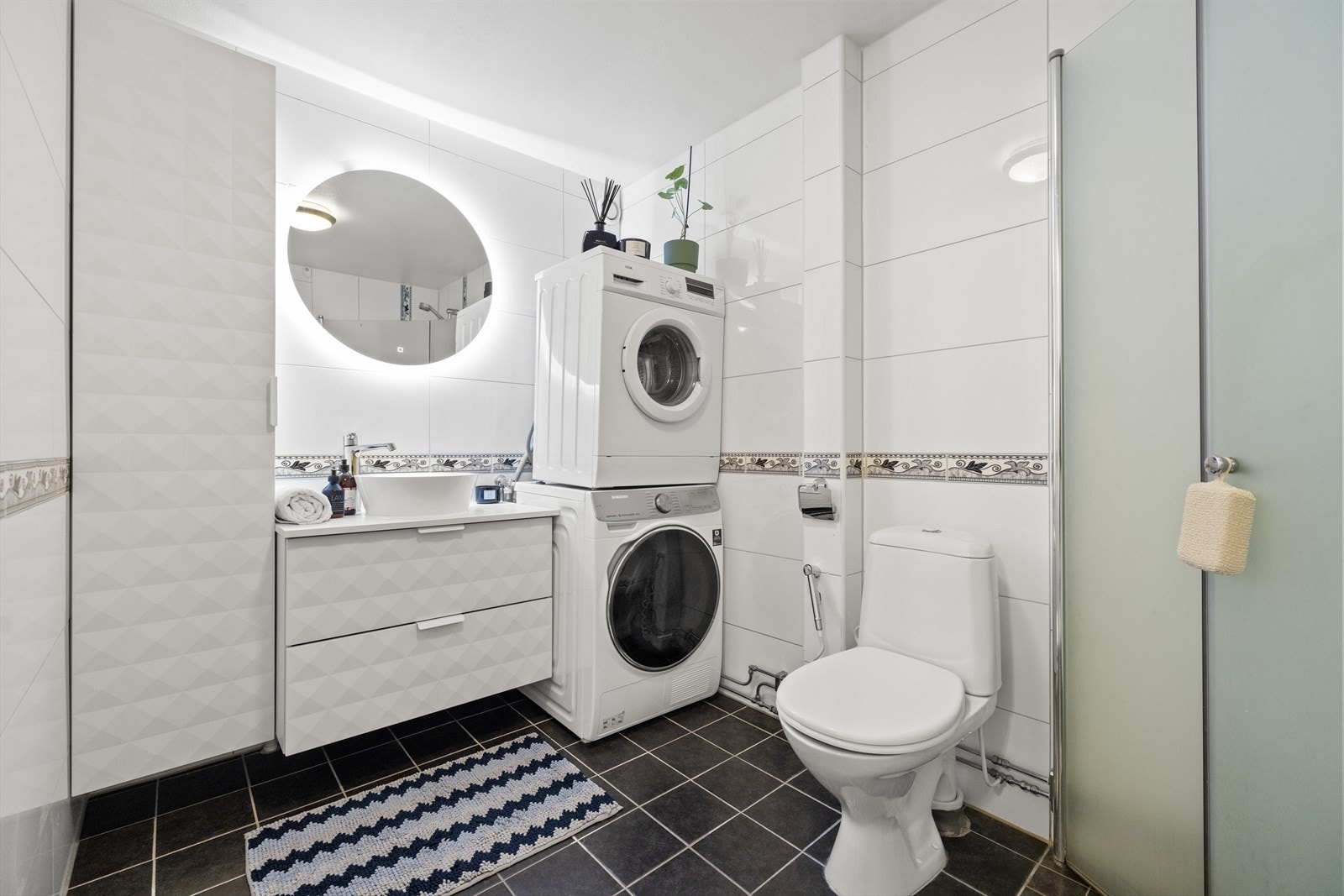 Flislagt pent bad fra 2010 med servant med underskap og gulvstående toalett. Opplegg for vaskesøyle. Galleribilde