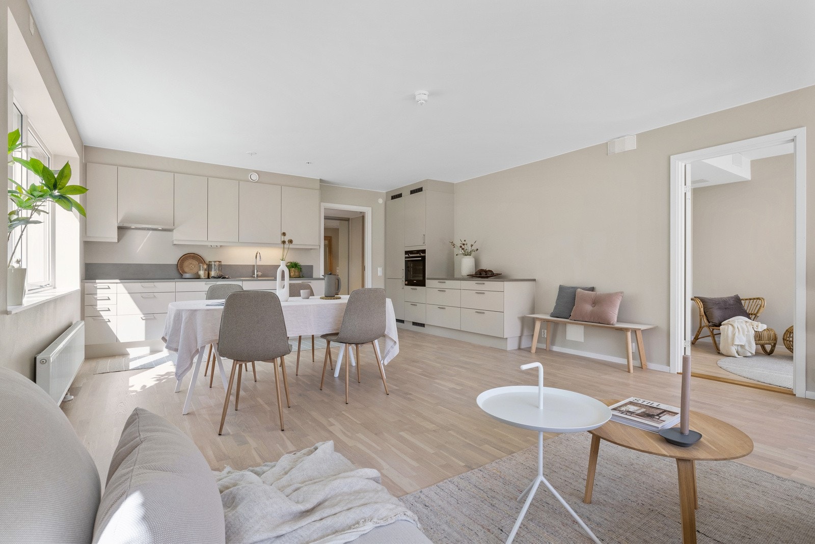 Kjøkkeninnredning med slette fronter i lys beige. God oppbevaringsplass i innredning. Galleribilde