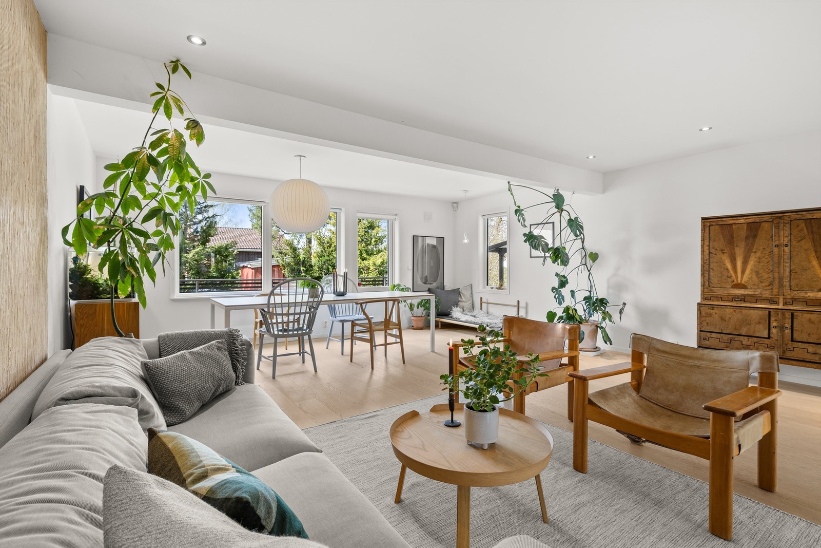 Solrik stue/spisestue med 1-stavs parkett på gulv og downlights i tak. Store vindusflater som fanger lys fra tre himmelretninger sørger for at rommet bades i lys. Galleribilde