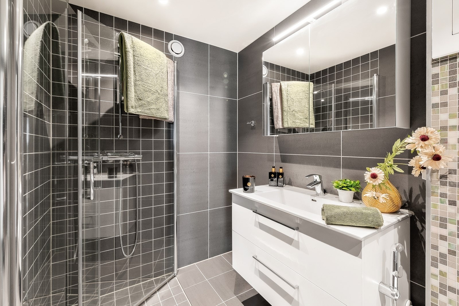 Badet er utstyrt med dusjhjørne med innfellbare glassvegger, vegghengt WC, servantinnredning med skuffer og overskap. Galleribilde