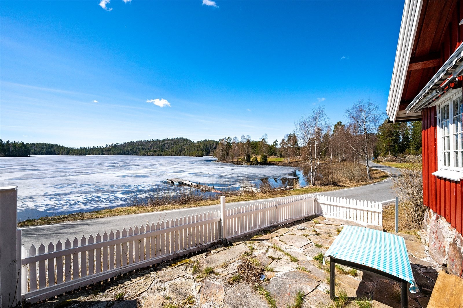 Fantastisk utsikt mot Vegår. Steinbelagt uteplass med stakittgjerde mot veien foran bryggerhuset. Galleribilde