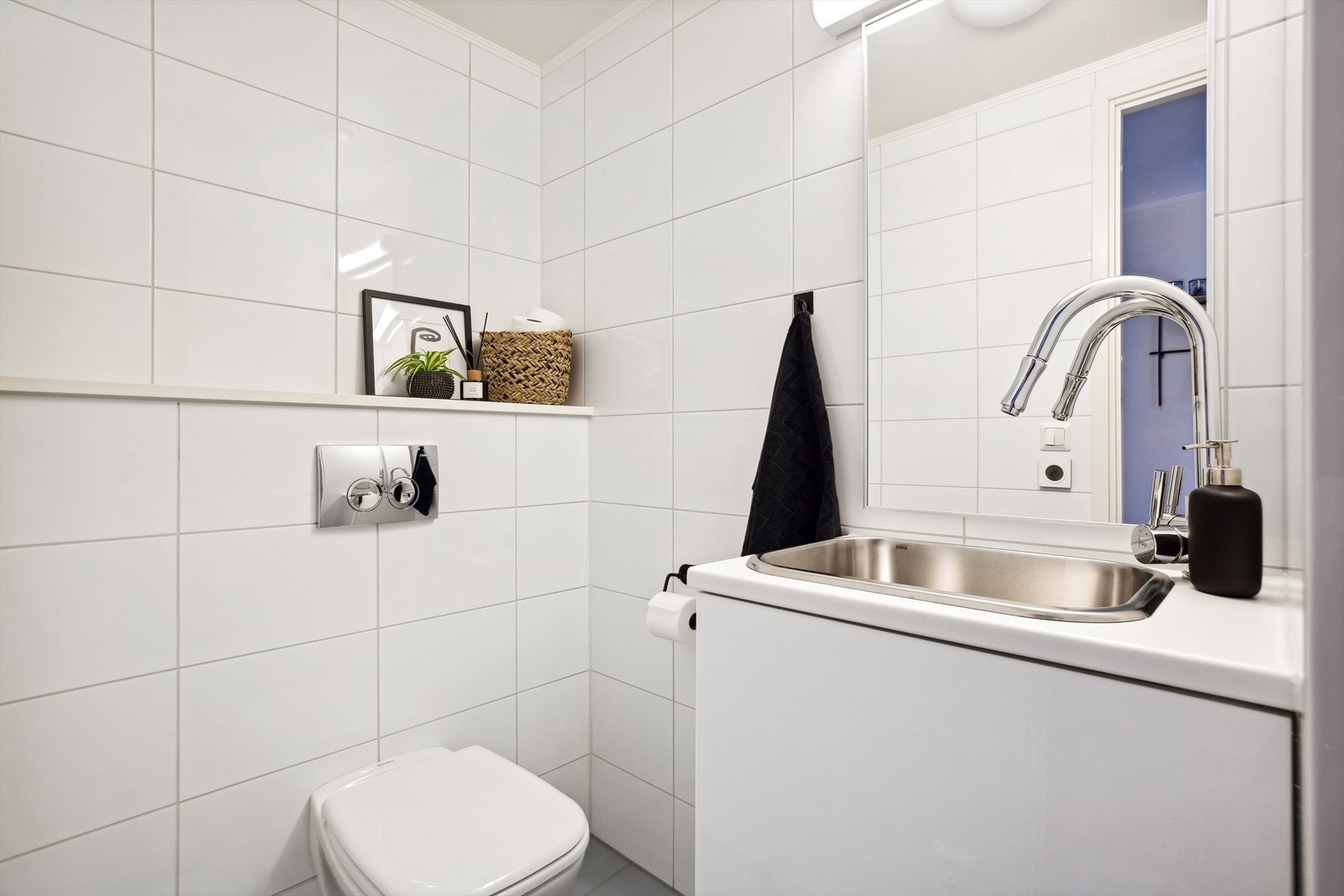 Wc-rommet ligger praktisk plassert rett ved ytterdøren og har flislagte overflater, veggmontert toalett og innredning med nedfelt servant og underskap. Galleribilde