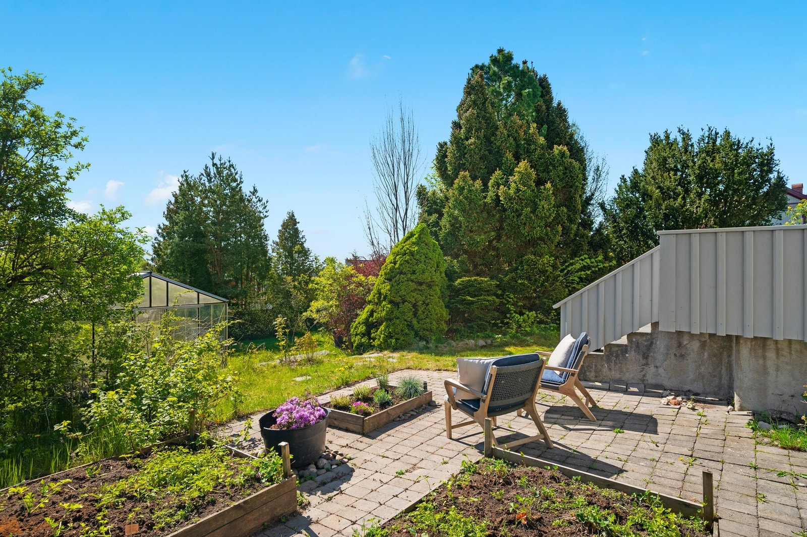 Plass til å sette utemøbler og solstoler på hellelagt område i hagen Galleribilde