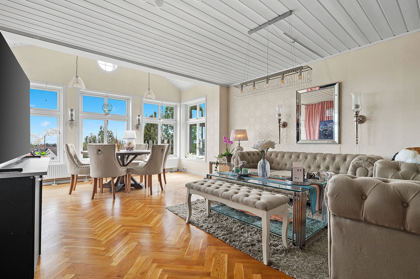 Stuen har en meget generøs takhøyde og det er rikelig med vinduer. Høyttaler i tak og radiatorer Galleribilde