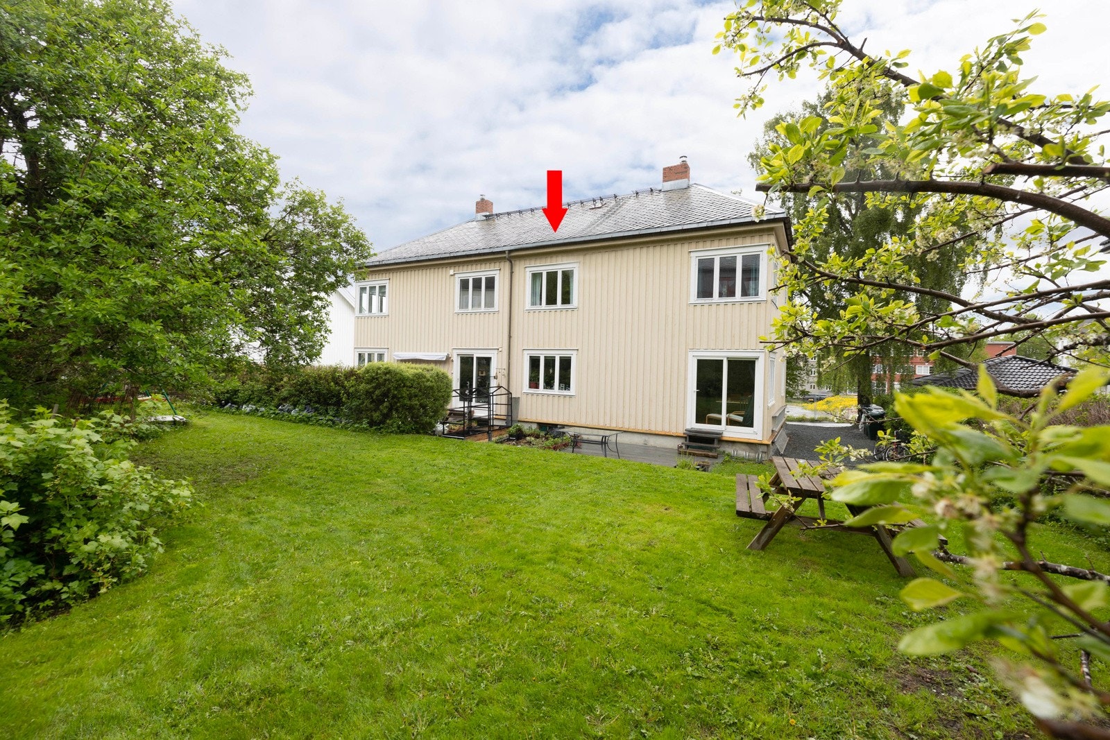 Sameiets hage og fasade bakside. Rød pil markerer leilighetens plassering. Galleribilde