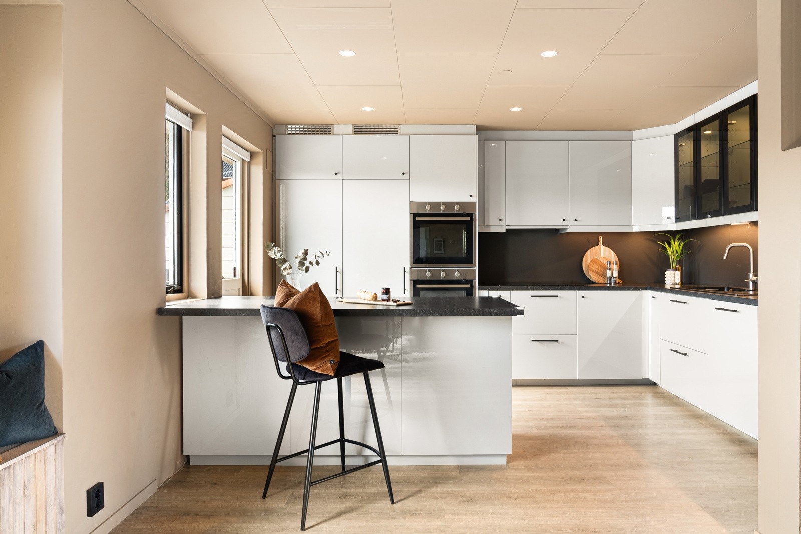 Flott ikea-kjøkken med slette fronter, to glasskap og laminat benkeplate med nedfelt vask av stål. Galleribilde