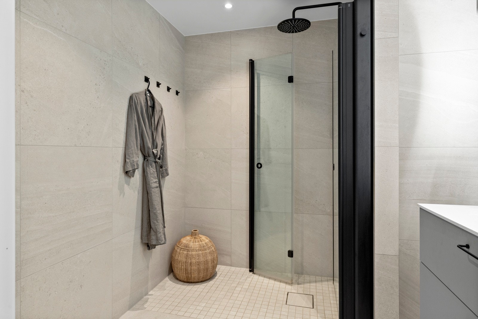 Det er downlights og varmekabler, og badet har et dusjhjørne med regnfallsdusj, integrerte dusjhyller, mosaikkfliser og innfellbare glassdører i sort innramming Galleribilde