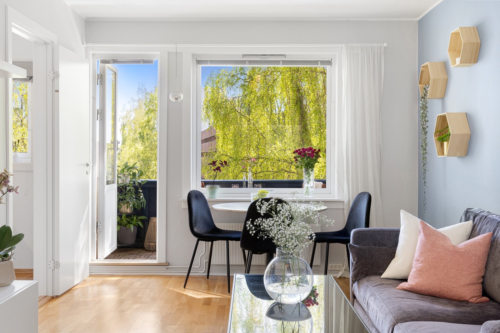 Stuen har et stort vindu og en balkongdør i glass på den ene siden av rommet som gir rommet rikelig med naturlig lys og et hyggelig utsyn. Galleribilde