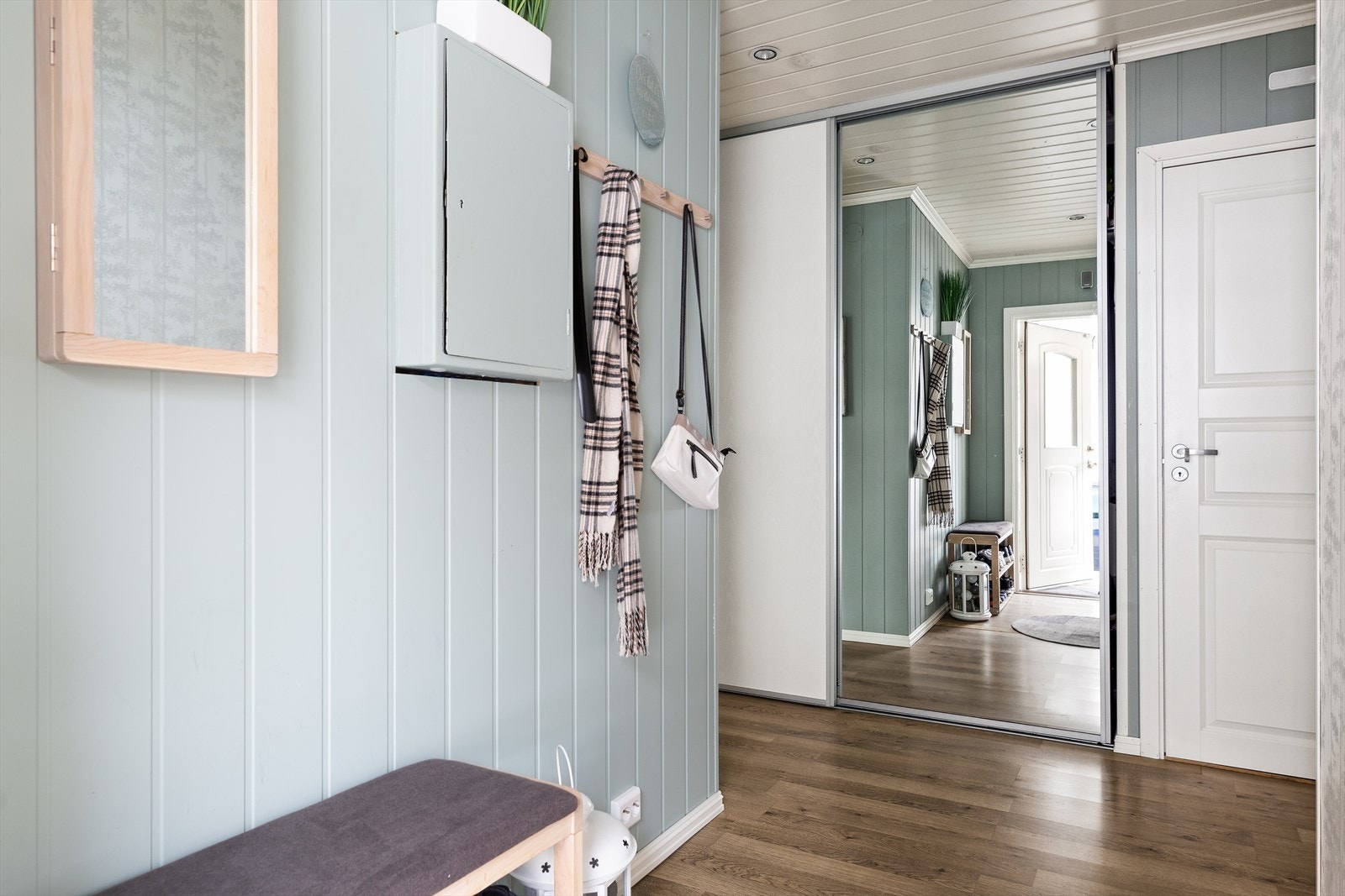 På veggen er det montert knaggrekke og litt lengre inn er det skyvedørsgarderobe. Galleribilde