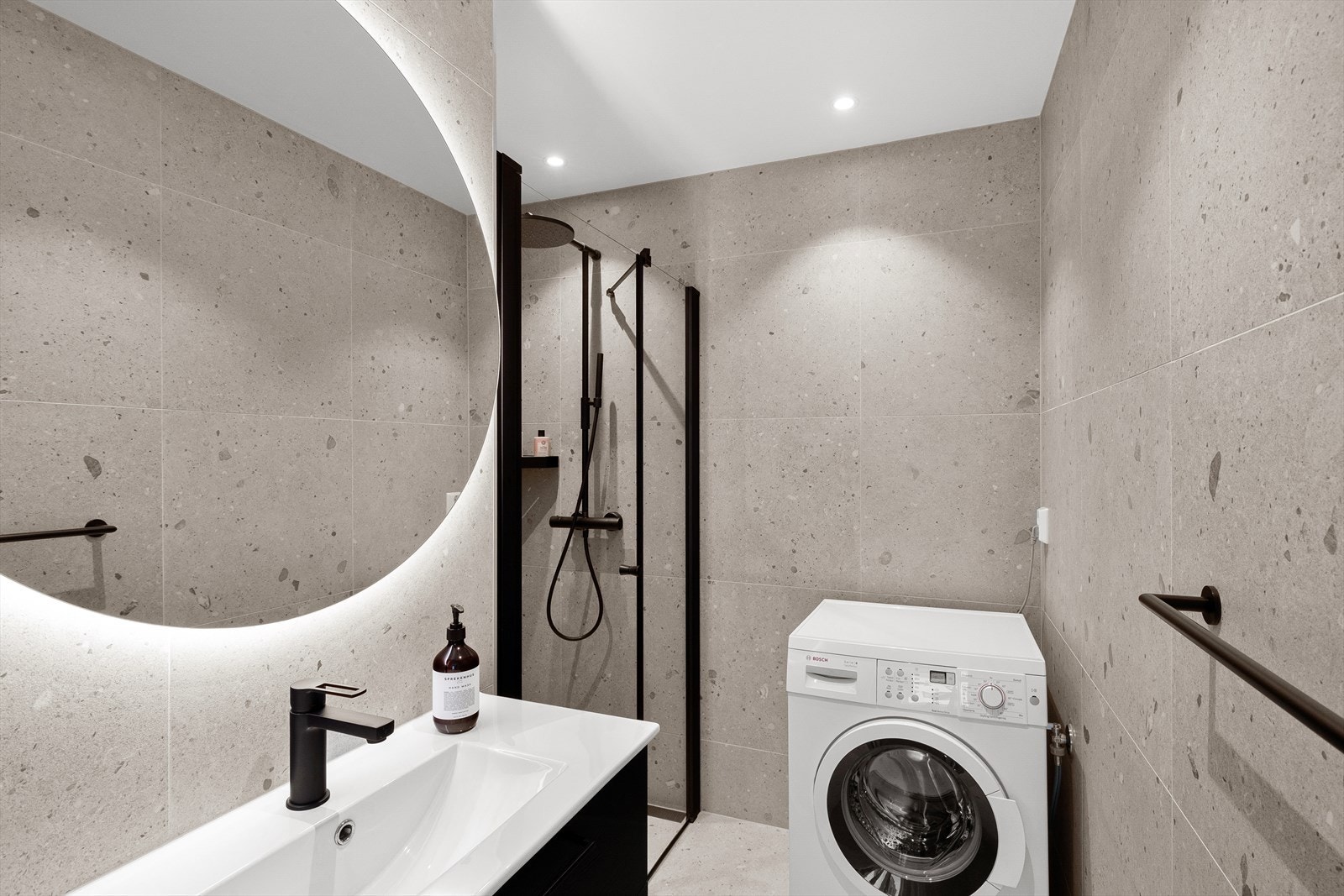 Badet har åpen dusj, servant med speil og plass for vaskemaskin/tørketrommel Galleribilde