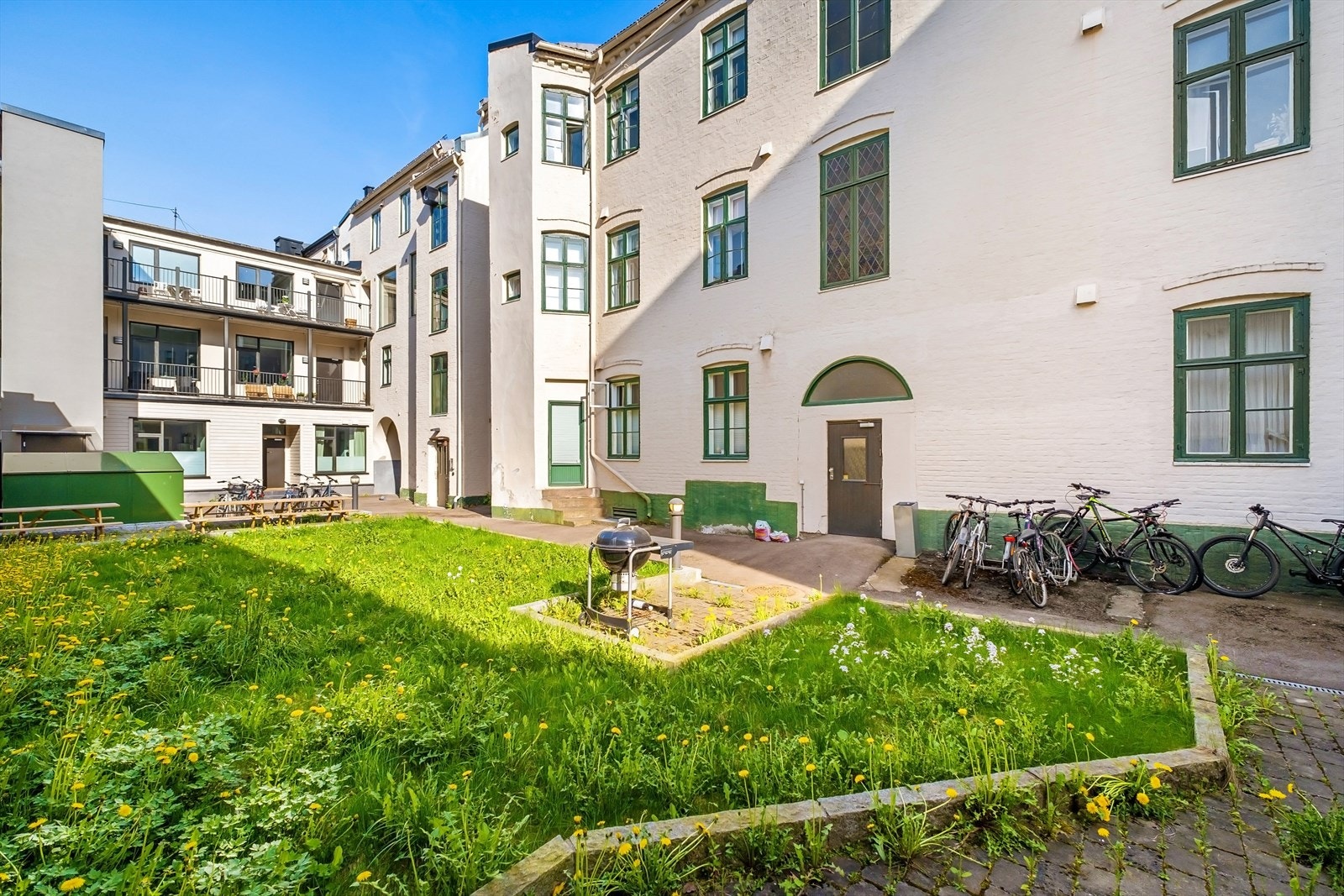 Hyggelig bakgård med plen, beplantning, grill og sittegrupper Galleribilde