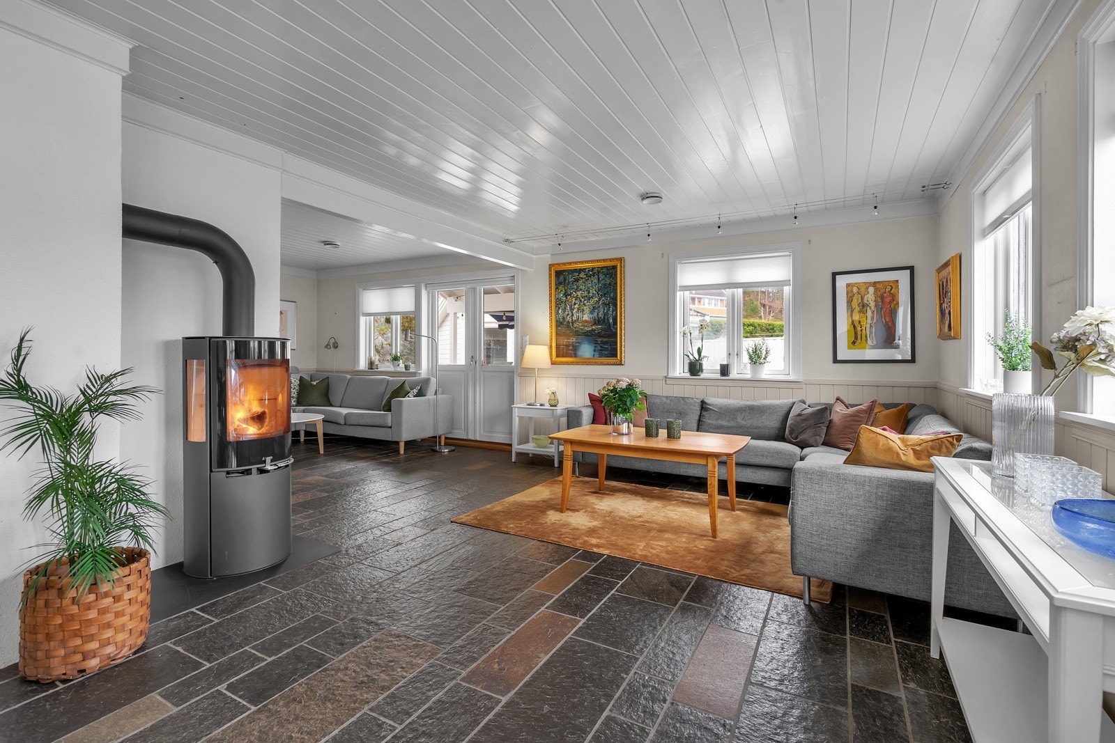 Vinkelstue med peisovn og utgang til støpt terrasse og hage Galleribilde