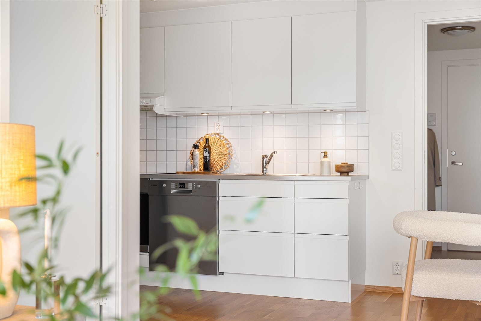 Stilrent kjøkken bestående av hvite, glatte fronter og benkeplate av laminat med nedfelt vask- og skyllekum. Galleribilde