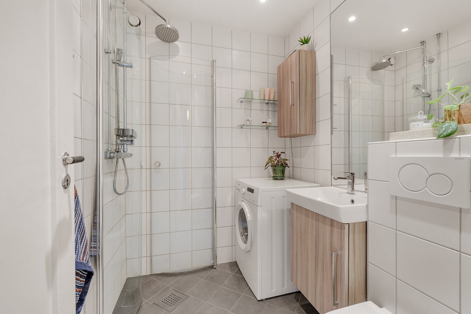 Pent, flislagt bad med dusj, opplegg for vaskemaskin, servant med underskap og veggmontert klosett Galleribilde