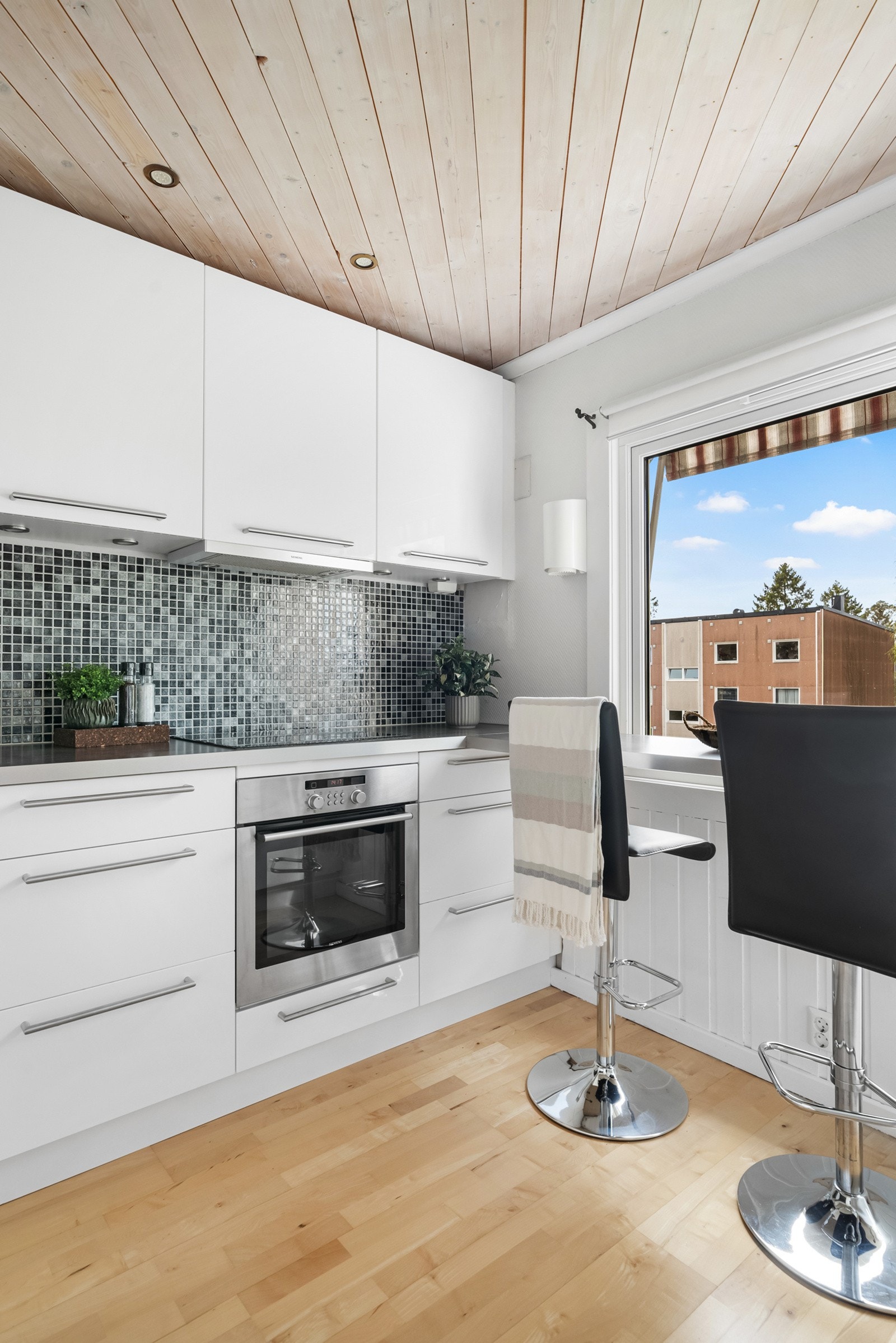 Over benken er det god belysning og mosaikkfliser som gjør det enkelt å holde rent. Integrert i innredningen har kjøkkenet både induksjonstopp, stekeovn, oppvaskmaskin og kjøle/fryseskap. Galleribilde