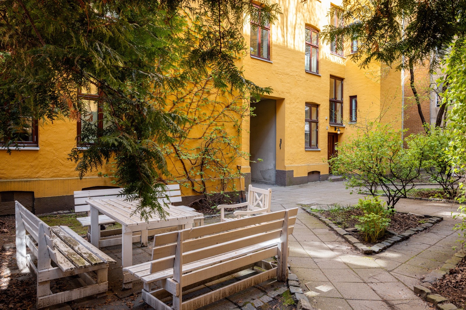 Nydelig, opparbeidet bakgård med sittegrupper, beplantning og trær. Galleribilde