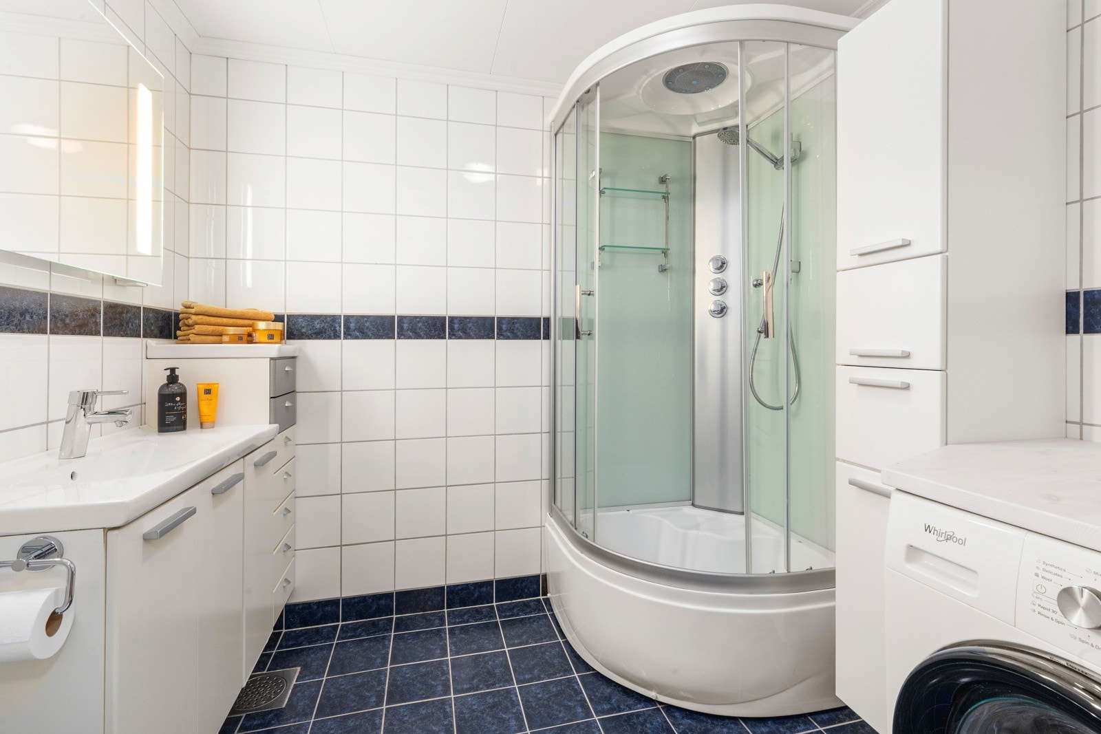 Flislagt bad med dusjkabinett og opplegg for vaskemaskin. Galleribilde