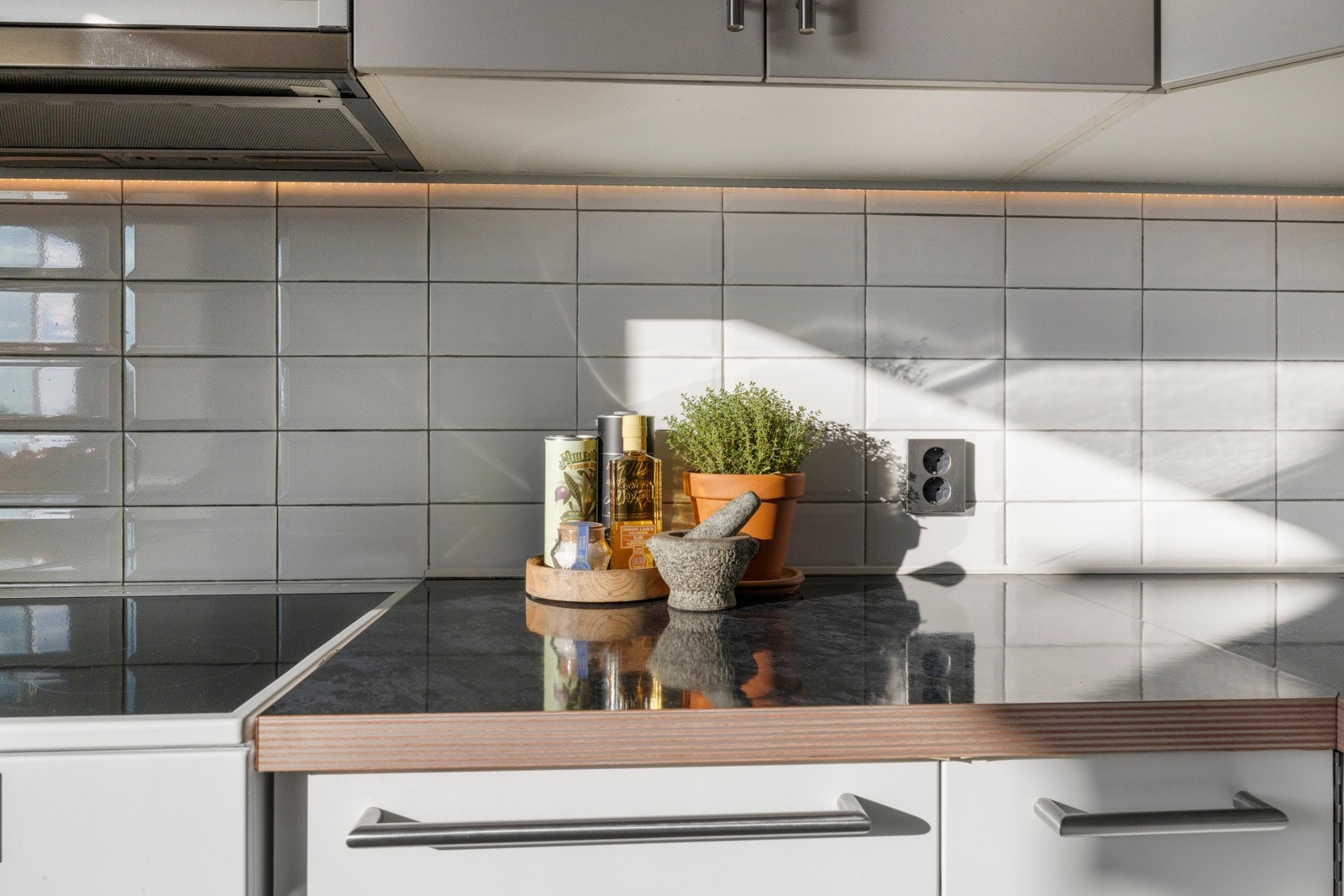 Veggene over benken er kledd med hvite fliser, og under overskapene er det montert god benkebelysning Galleribilde