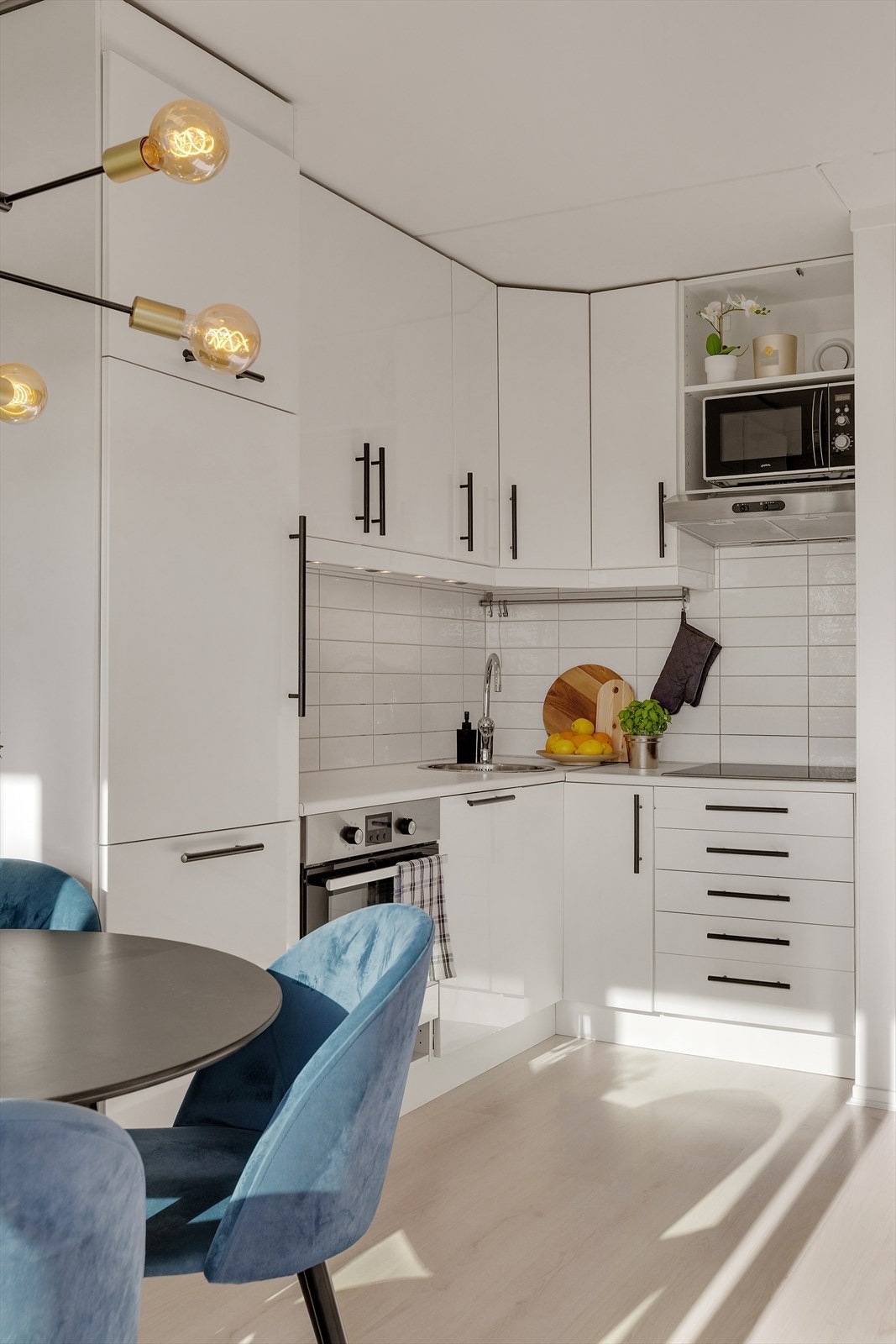 Kjøkkeninnredning med glatte fronter, laminert benkeplate, oppvaskkum, ventilator og fliser over benk. Galleribilde