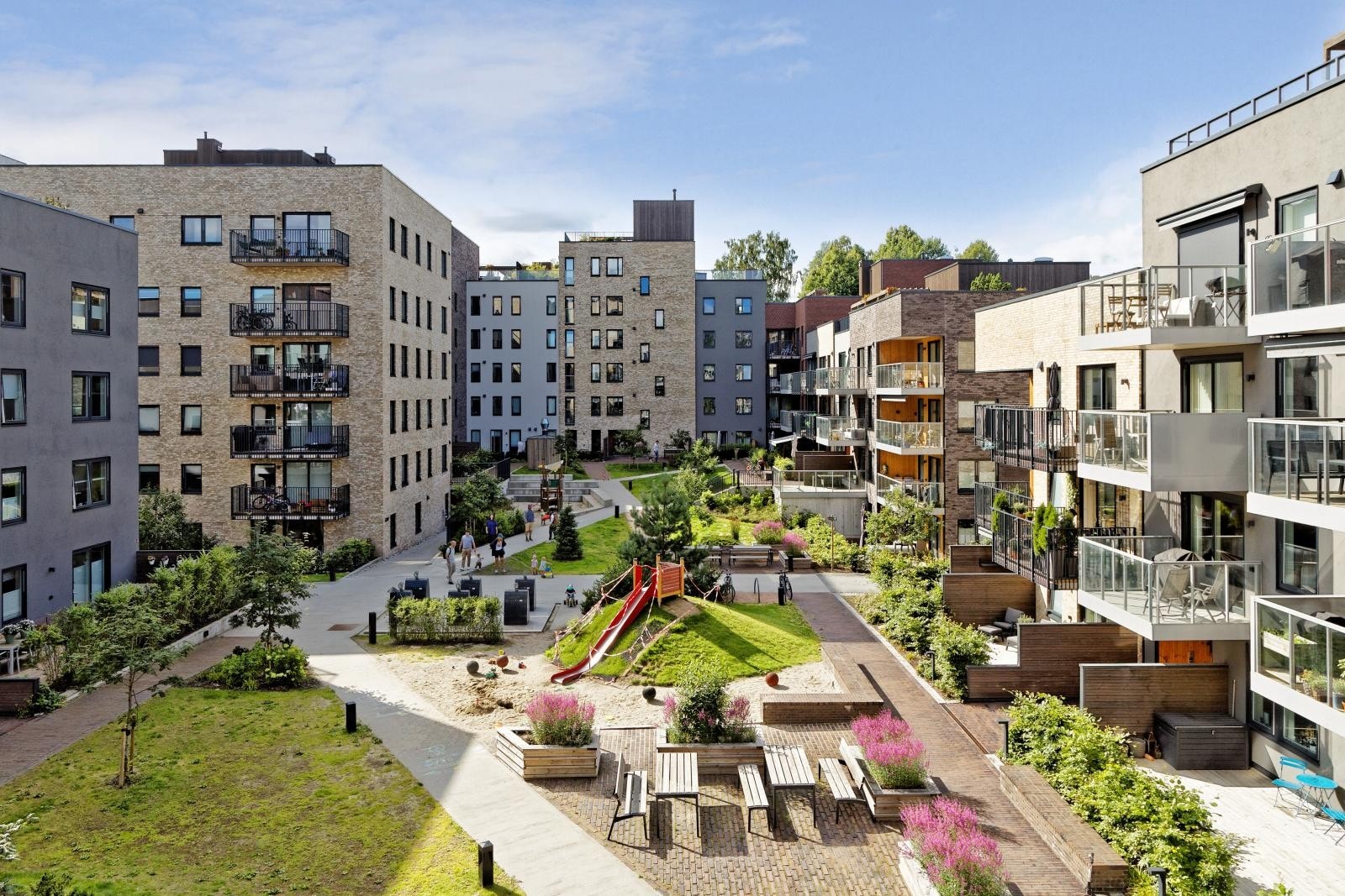 Flott bakgård med flere lekeapparater og sittegrupper for beboere Galleribilde