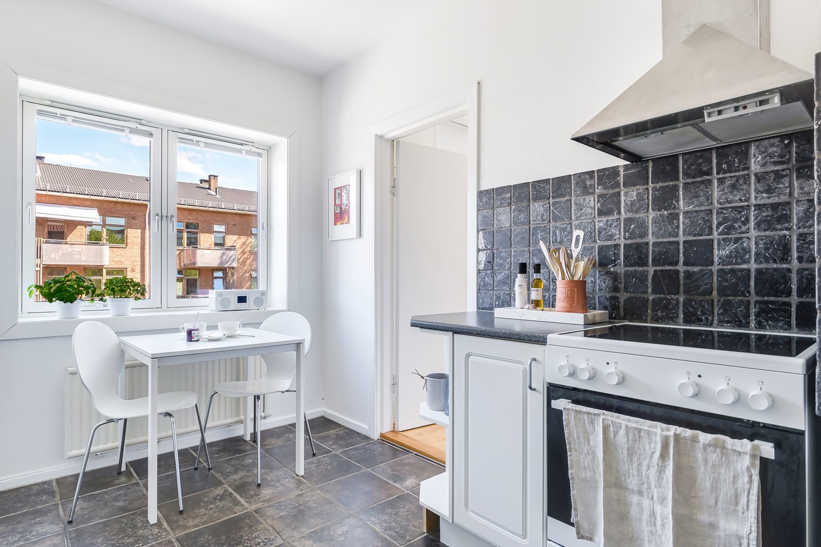 Kjøkkenrommet har plass for liten spiseplass under kjøkkenvinduet, med utsyn mot Mor Go'hjertas vei, en traffikkstille gate Galleribilde