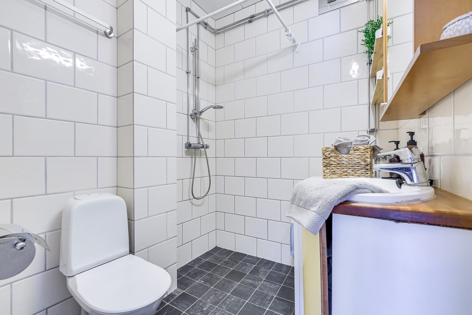 Baderom med lyse, flislagte overflater og opplegg for vaskemaskin Galleribilde