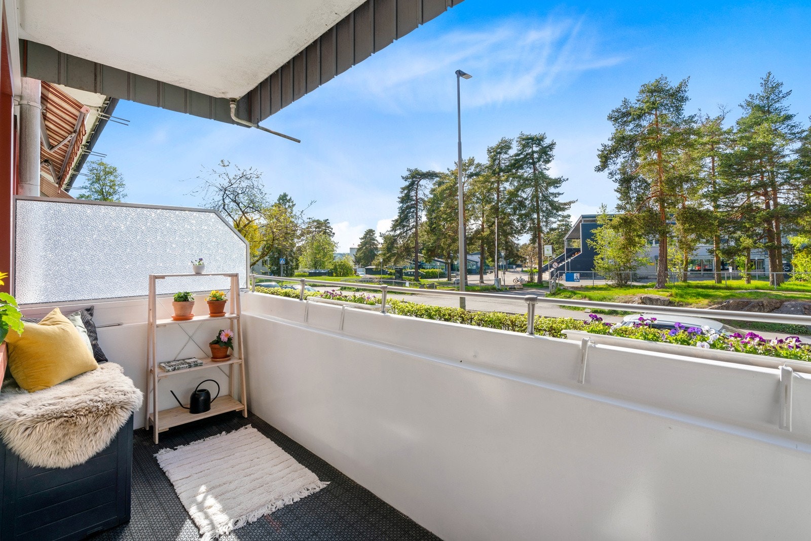 Balkongen har ellers dekke i betong belagt med plastheller, tett rekkverk med stålspiler øverst, og levegger i ruglete glass på sidene. Galleribilde