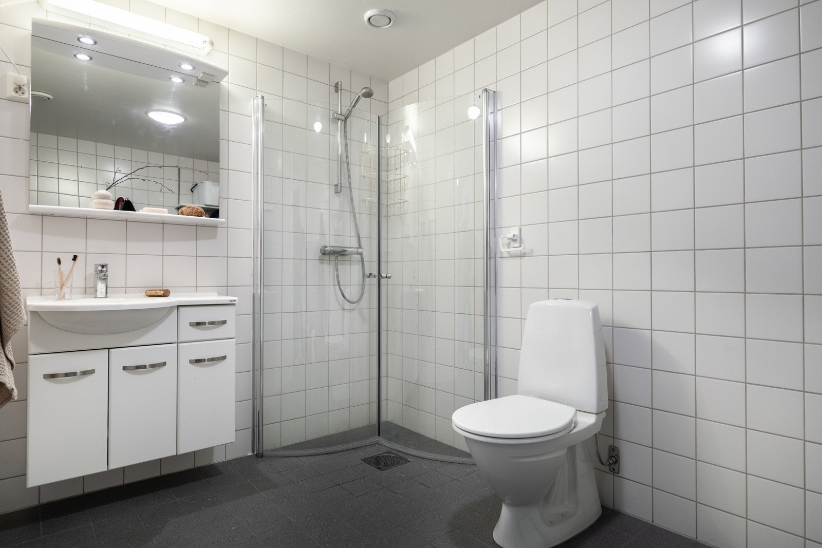 Badet er utstyrt med servantskap med ovenpåliggende servant, gulvstående toalett og speil over servant. Galleribilde