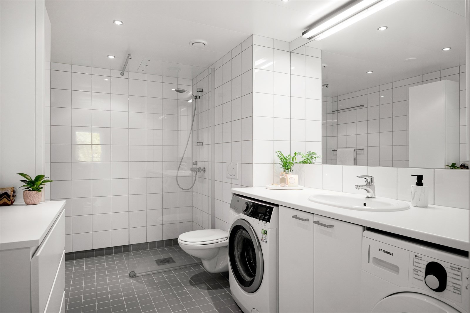 Stilrent flislagt baderom med elektrisk gulvvarme, downlights i himling og opplegg for vaskemaskin og tørketrommel. Galleribilde