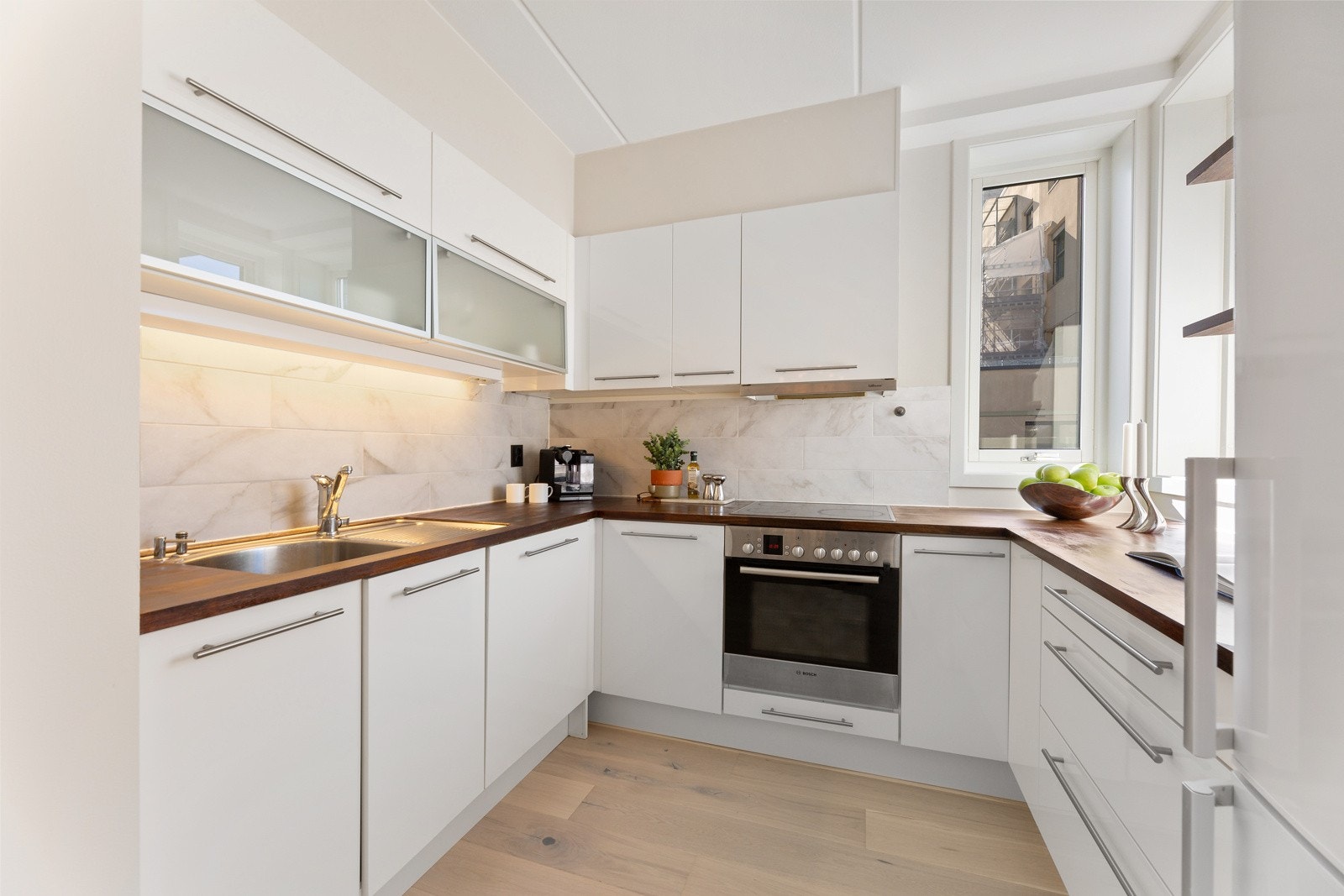 Lyst og pent kjøkken i U-form med gode oppbevaringsmuligheter i over- og underskap. Galleribilde