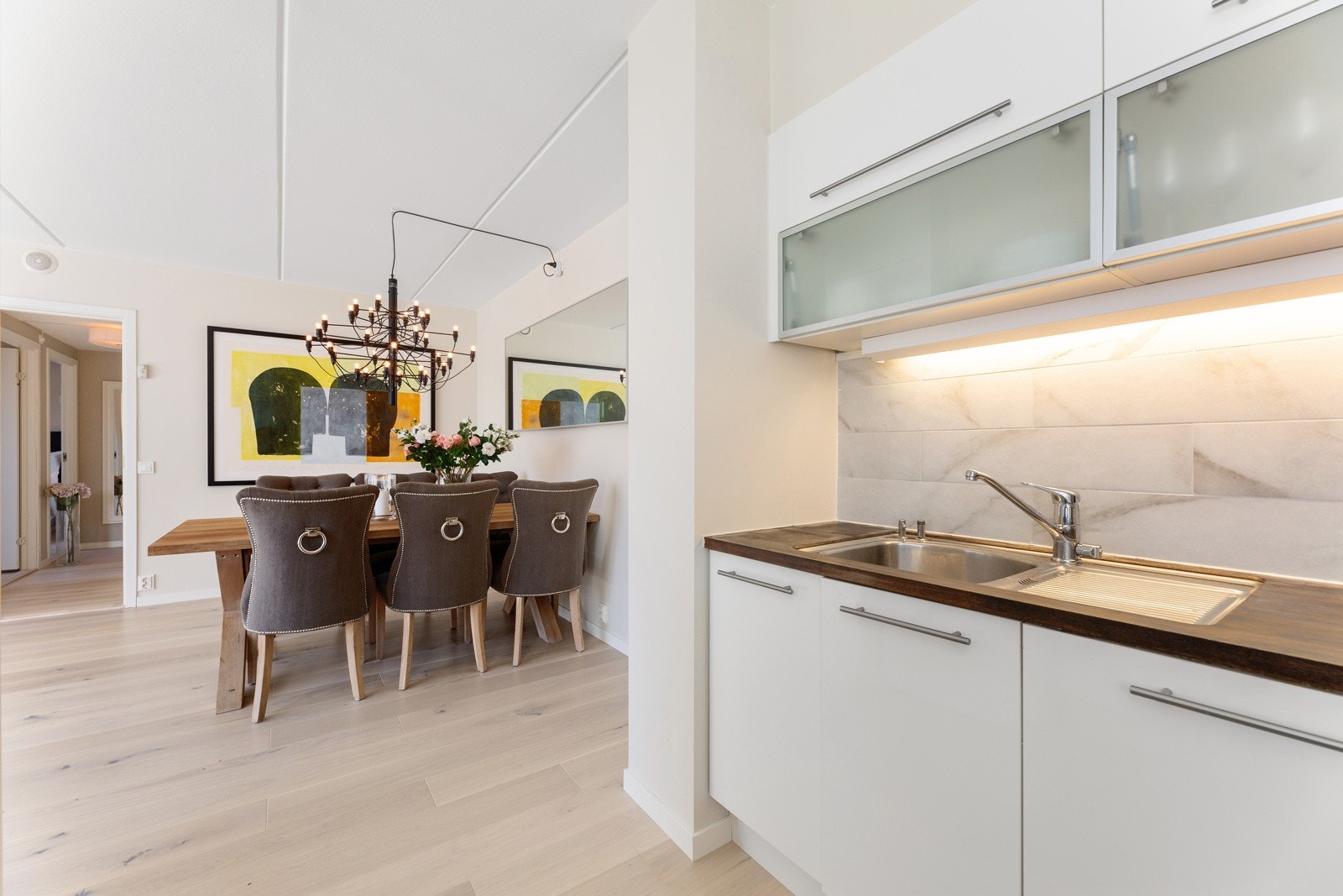 Innredning har glatte fronter, belysning og kledelige fliser over lys og tre benkeplate. Galleribilde