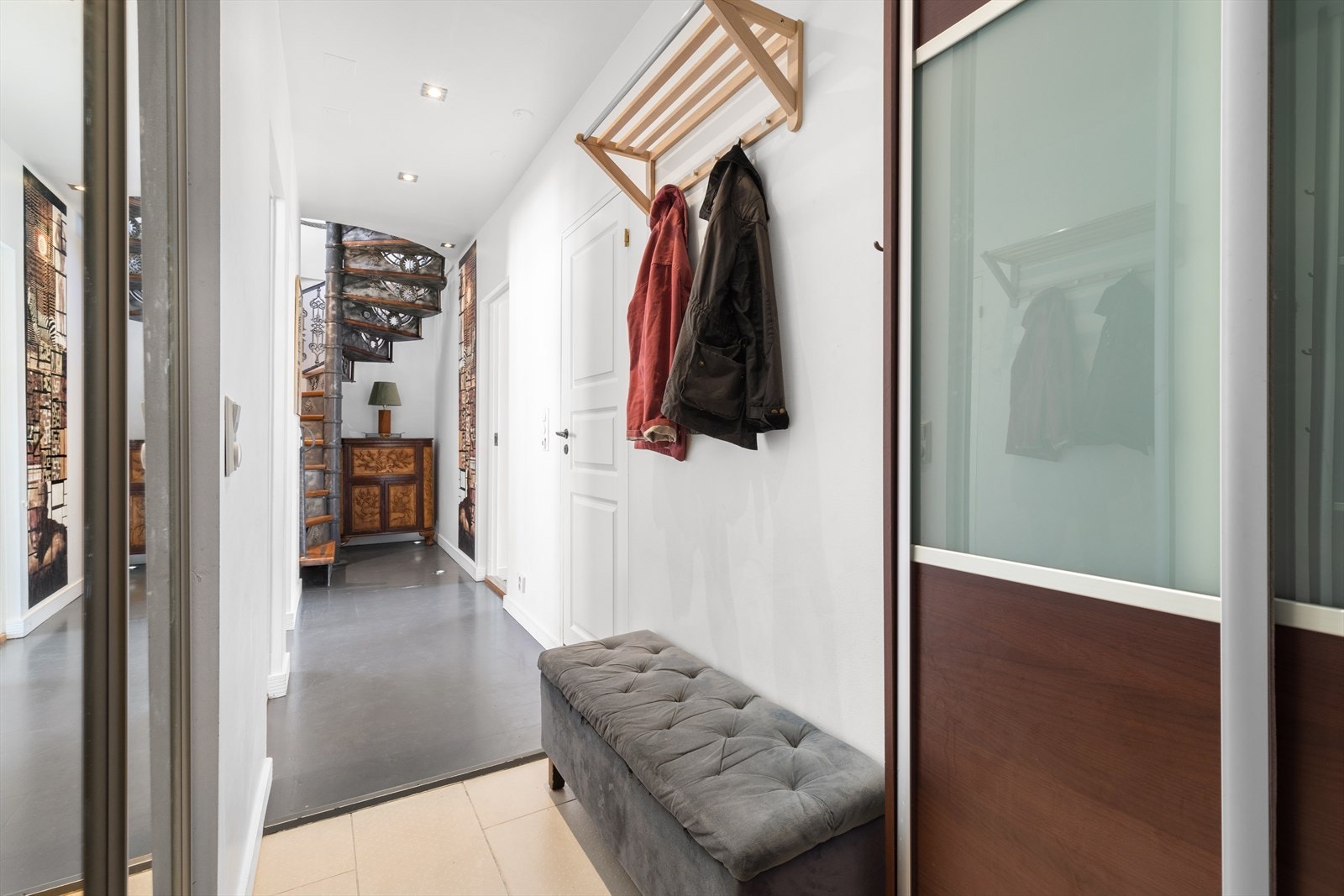 Flislagt inngangsparti i gangen. Plassbygget skyvedørsgarderobe på begge sider med opplegg for vaskemaskin i skapet til venstre. Galleribilde