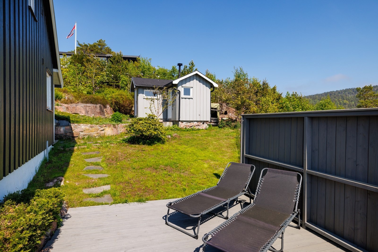 Tomten er opparbeidet med noe gressplen, beplantninger og prydbusker. Flaggstang på eiendommen. Galleribilde