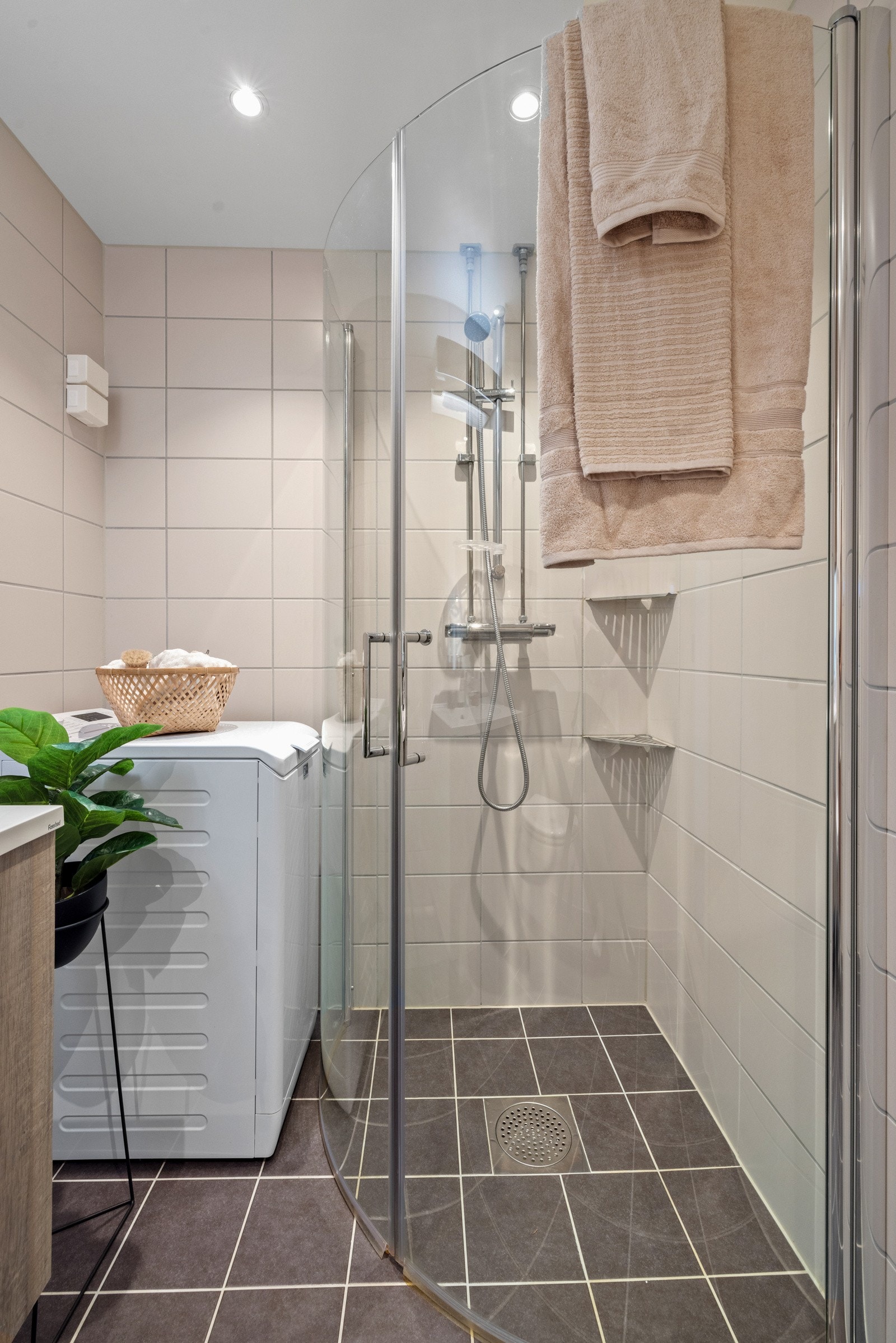 Videre har badet et vegghengt toalett, opplegg for vaskemaskin og et dusjhjørne med innfellbare glassdører Galleribilde
