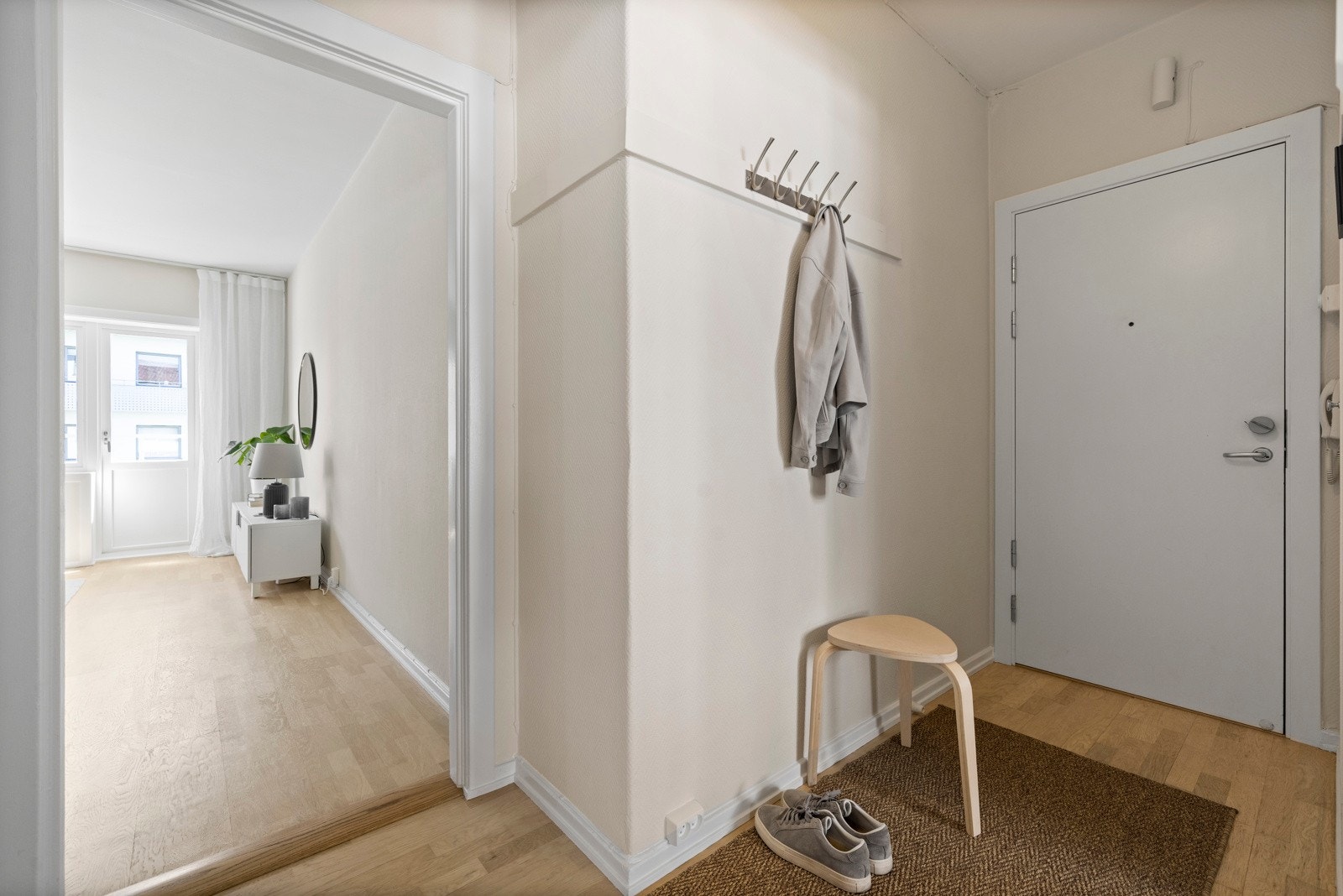 Lys og innbydende entré som ønsker deg velkommen inn, med plass til oppheng av ytterklær og sko Galleribilde