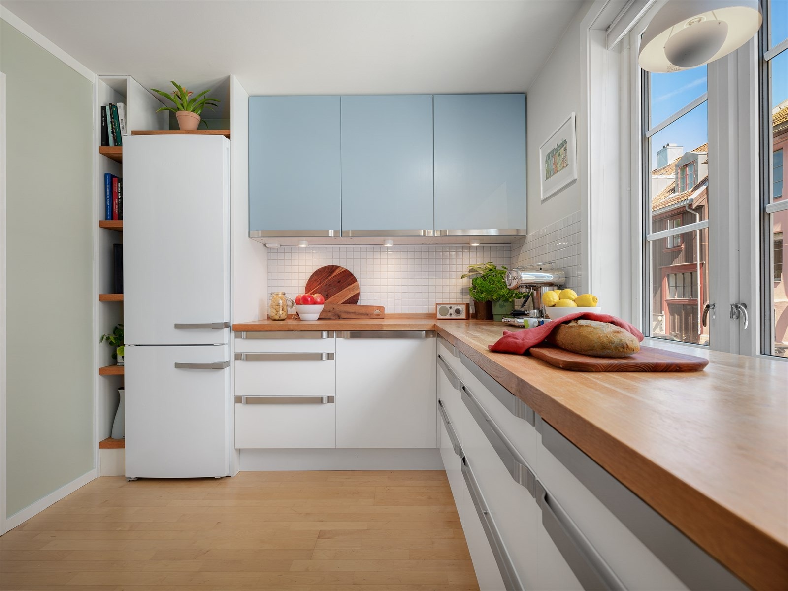 Innredningen består av lyse, glattlakkerte fronter fra IKEA med heltre eik benkeplate. Fliser over benk. Integrert komfyr med induksjons platetopp. Frittstående oppvaskmaskin og kjøl/frys. Galleribilde