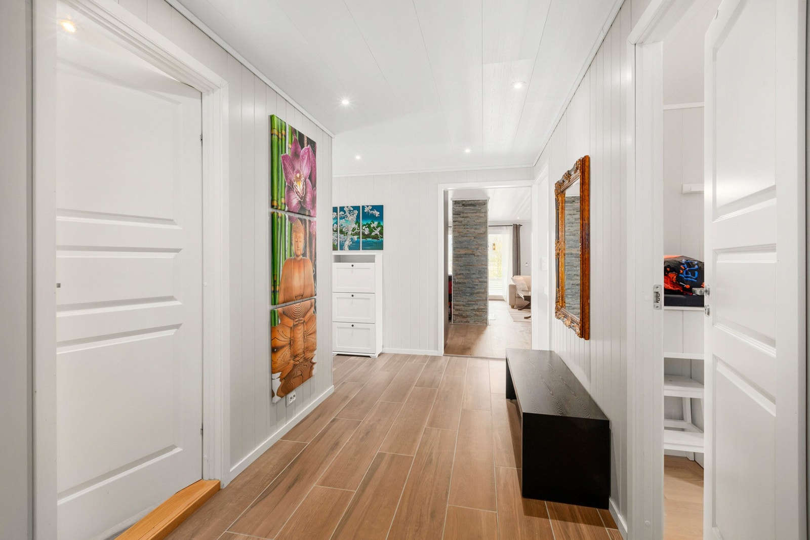 Romslig mellomgang i hovedetasjen med flis på gulv, gulvvarme, panelplater på vegger, plater og downlights i tak. Trapp og sikringsskap. Galleribilde