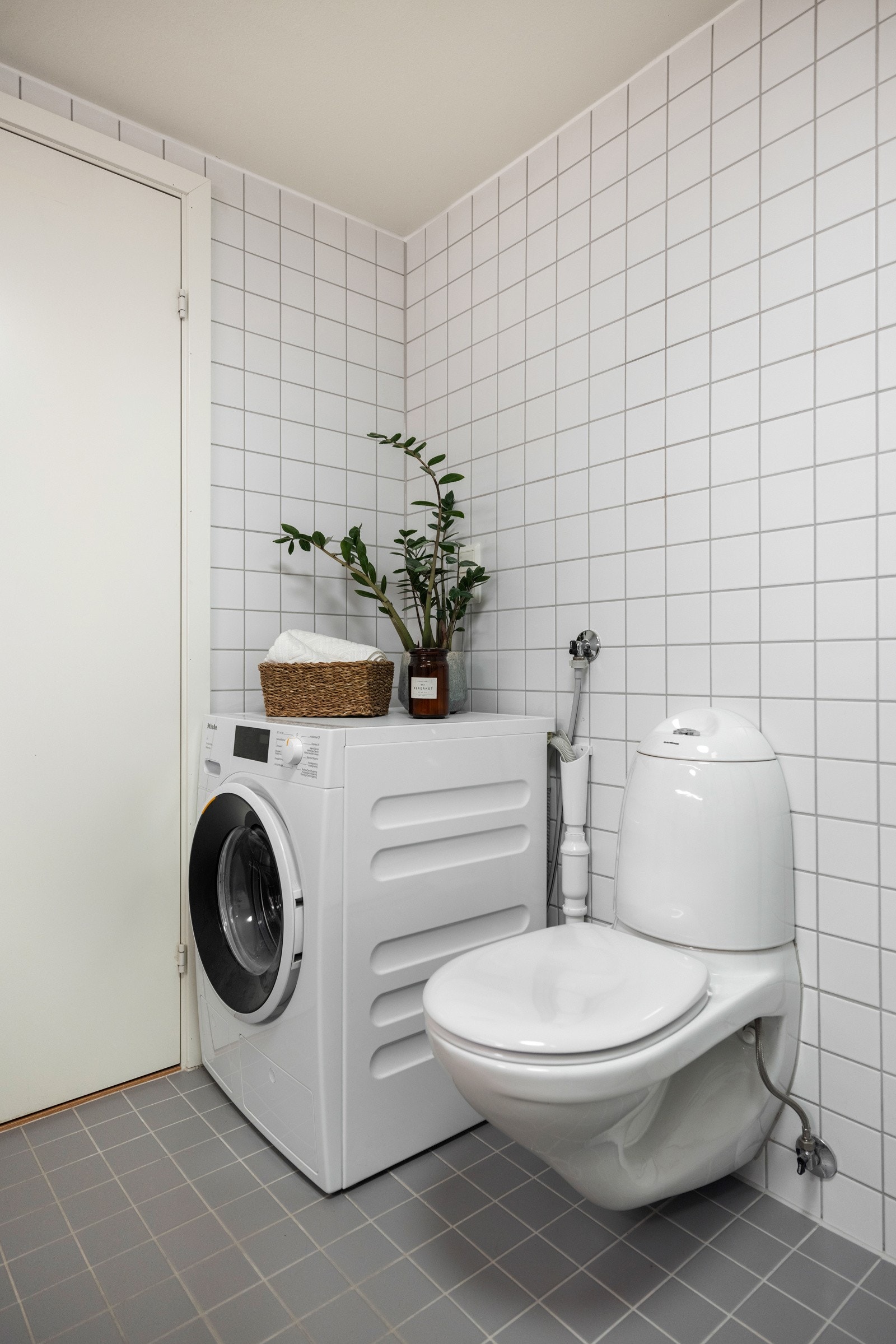 Veggmontert toalett med utenpåliggende sisterne samt opplegg for vaskemaskin Galleribilde
