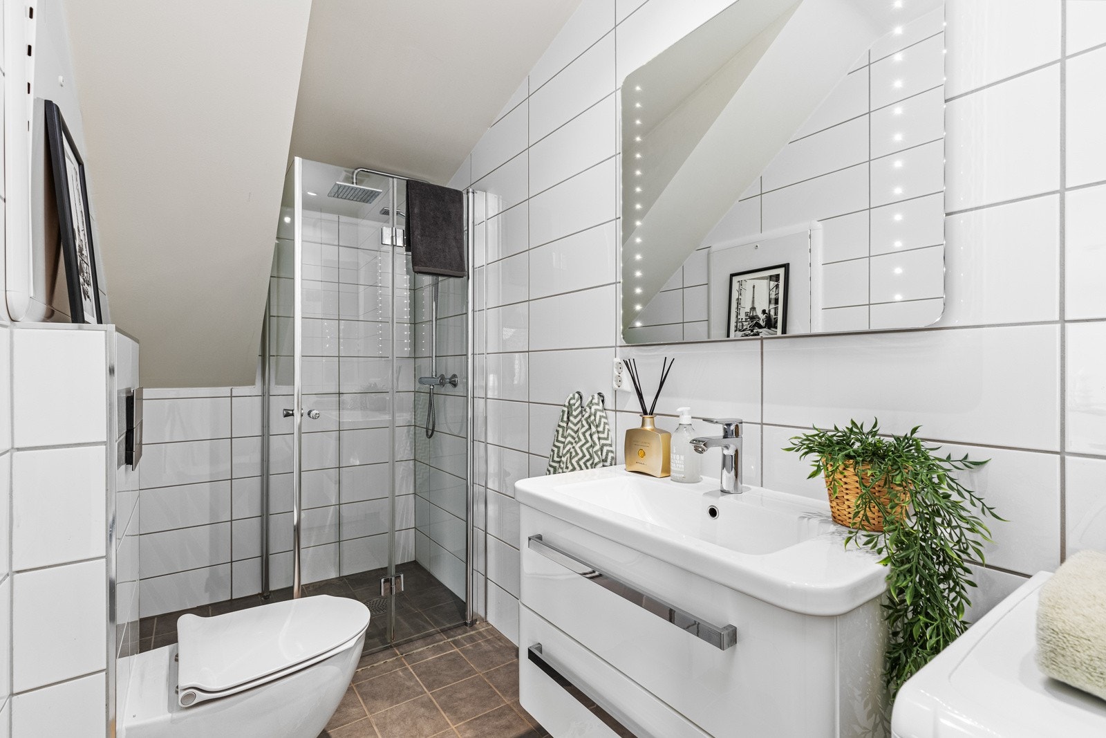 Smakfullt bad med flislagte flater, gulvvarme, opplegg for vaskemaskin, vegghengt wc, downlights og belyst speil. Galleribilde