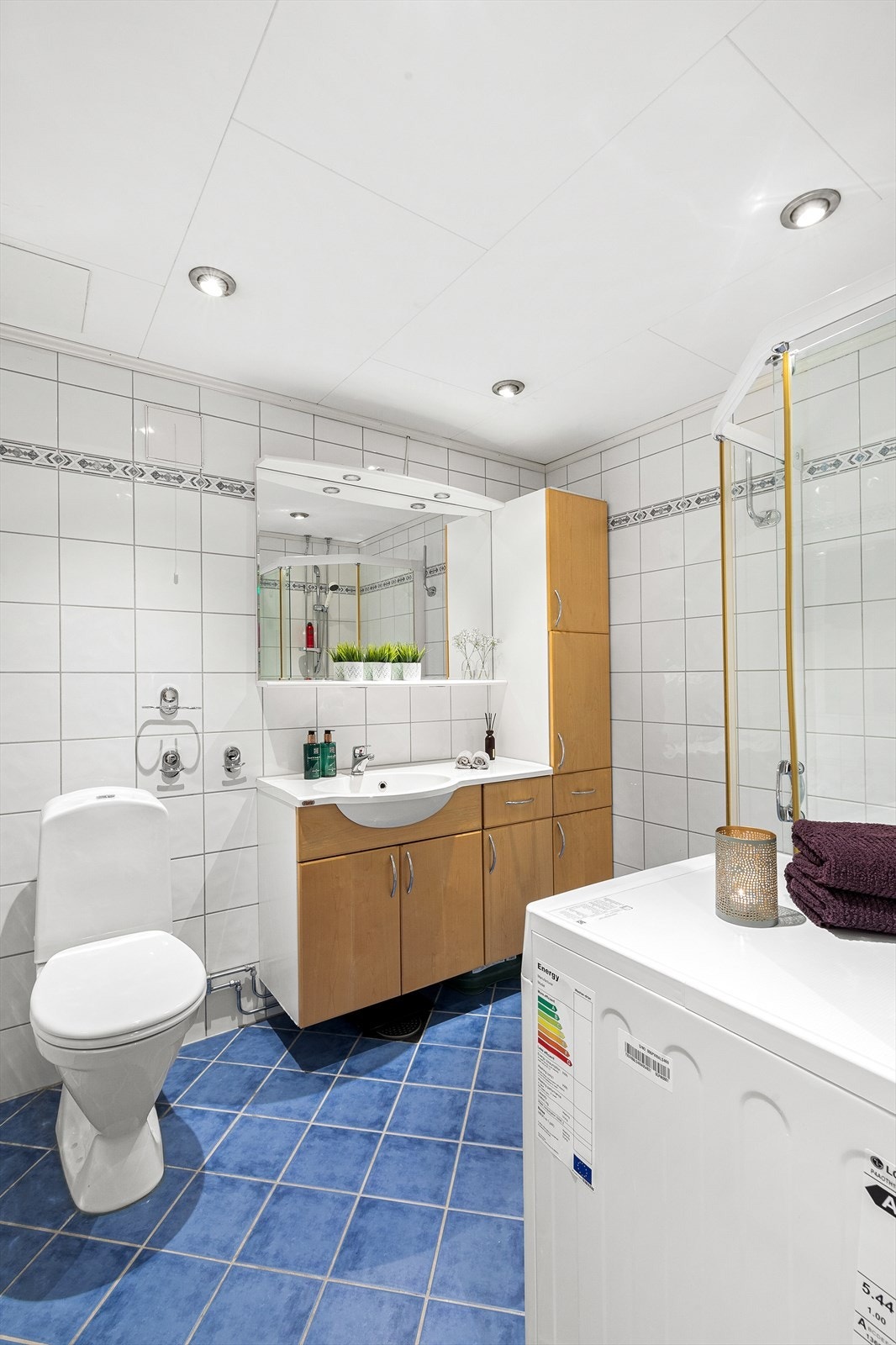 Badet har benkeskap og veggskap med glatte fronter, som gir et rent og elegant uttrykk. Det er også opplegg for vaskemaskin. Galleribilde